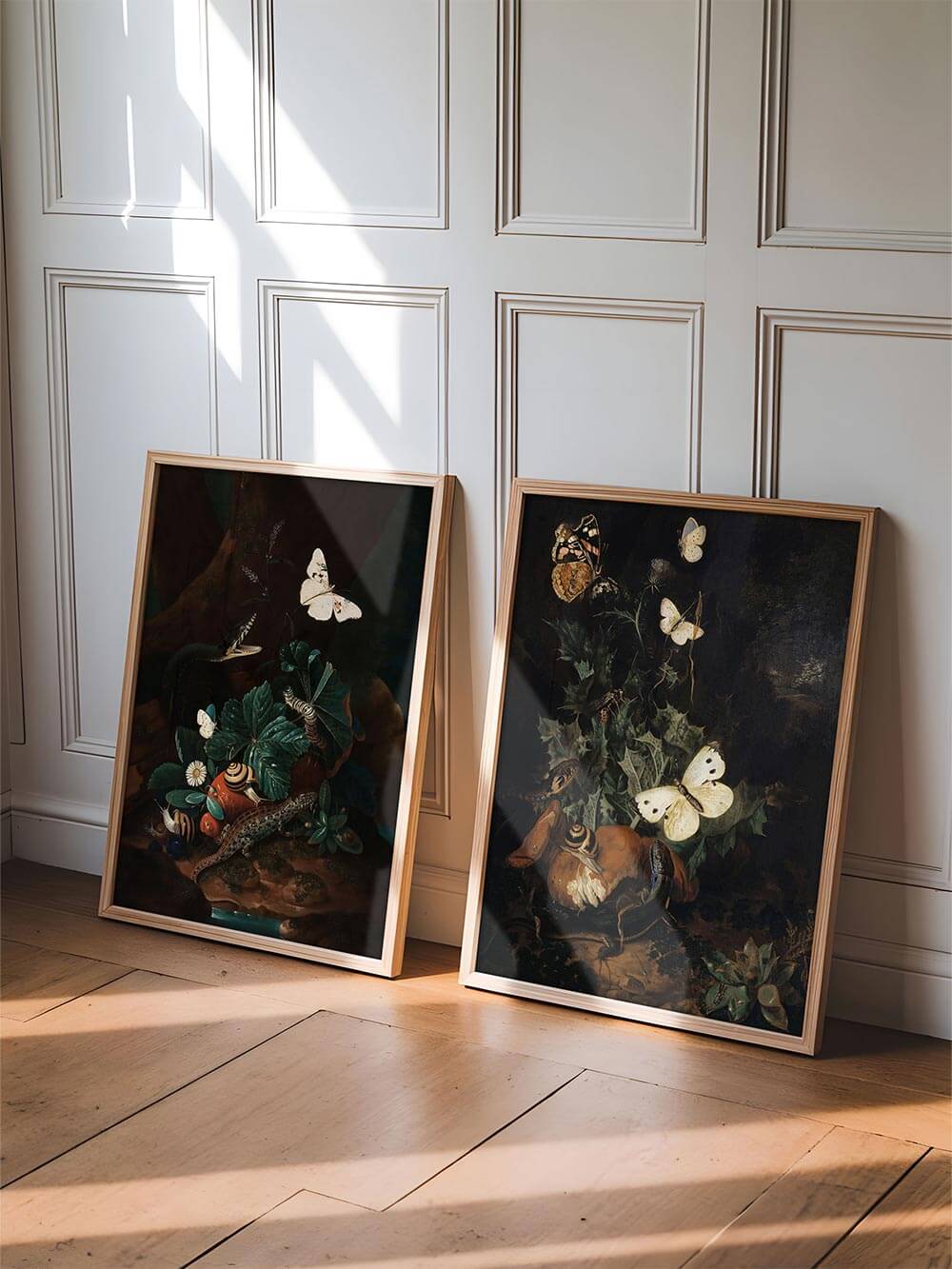 Zwei gerahmte Kunstdrucke mit dunklen Waldmotiven lehnen an einer Wand mit Wandvertäfelung. Die naturalistischen Stillleben wirken stimmungsvoll im Lichtfall.