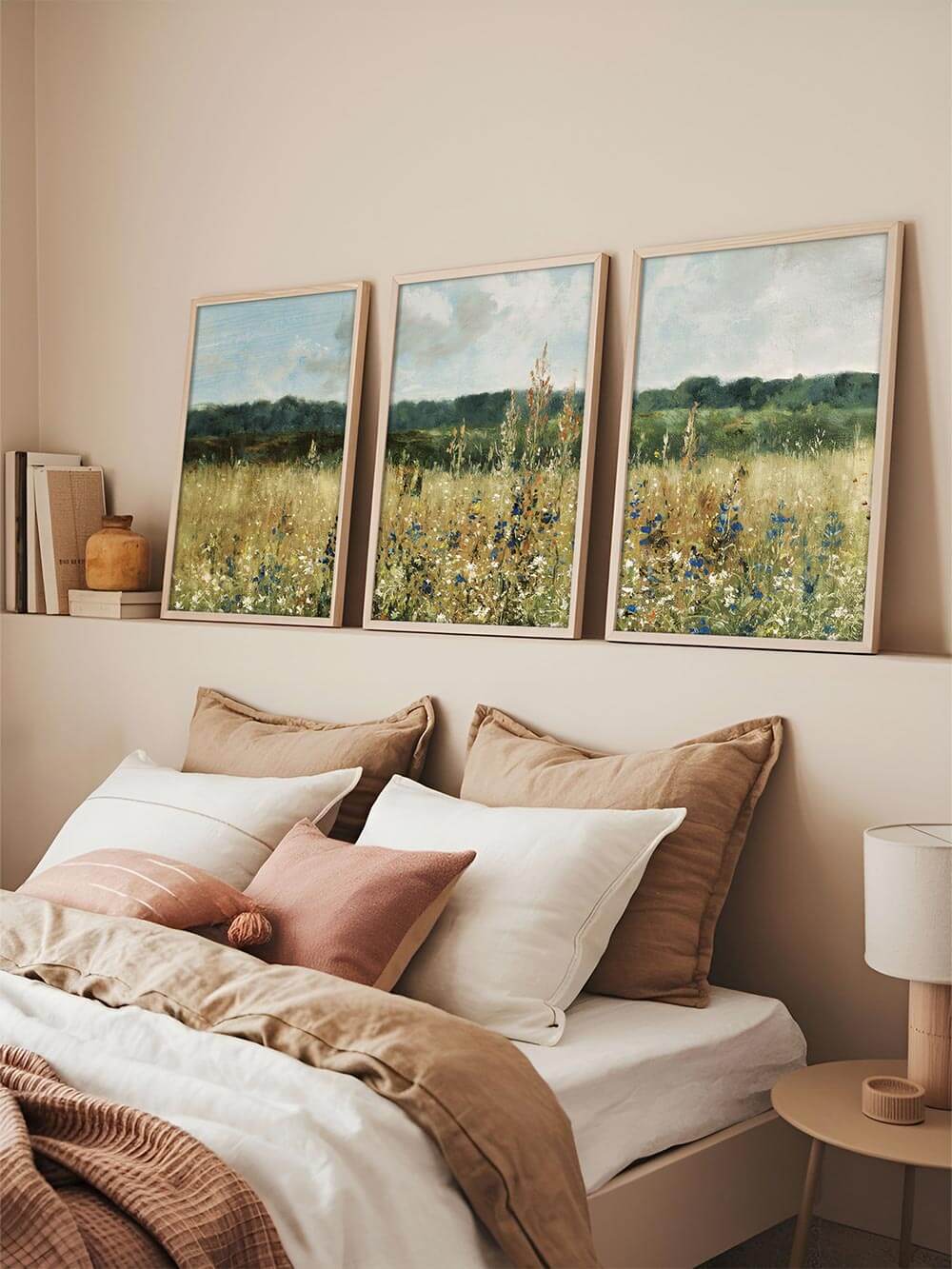 Die drei Wildblumen Kunstdrucke lehnen entspannt über einem Bett mit Leinenbettwäsche. Die ruhige Farbpalette fügt sich harmonisch in das naturnahe Farbkonzept ein.