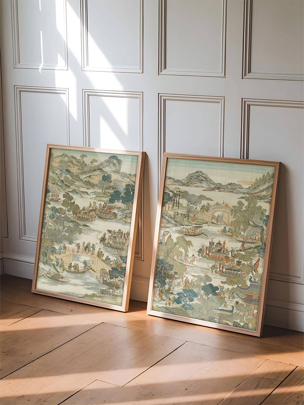 Zwei gerahmte Chinoiserie Poster an eine Wand gelehnt in einem hellen Raum, wodurch Größe, Proportion und dekorative Wirkung des zweiteiligen Wandbild-Sets realistisch gezeigt werden.