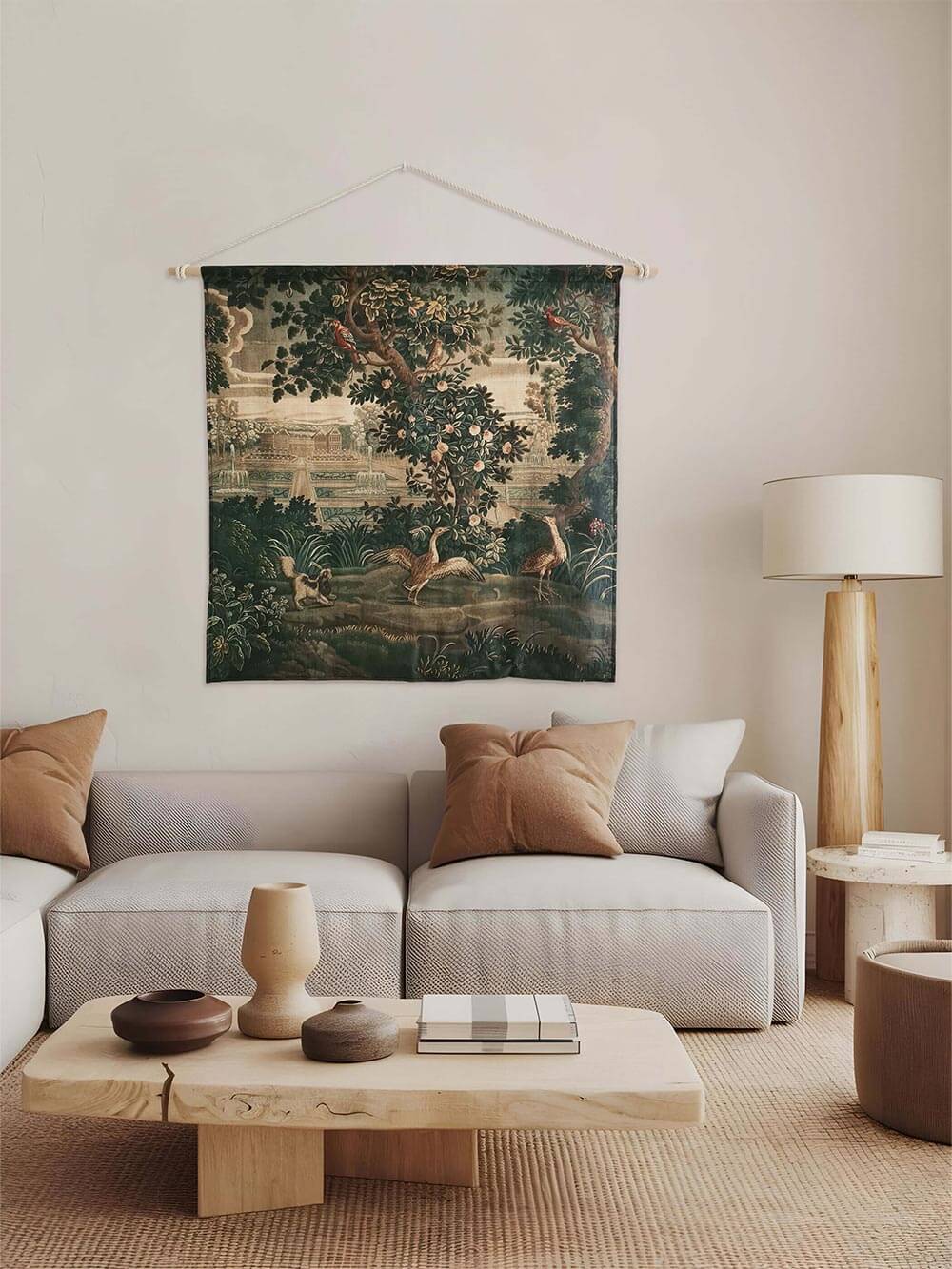 Rokoko Verdure Wandbehang über einem minimalistischen Sofa mit Erdtönen. Die detailreiche Gartenlandschaft mit Blüten, Vögeln und Fontänen verleiht dem Raum Tiefe und Eleganz.