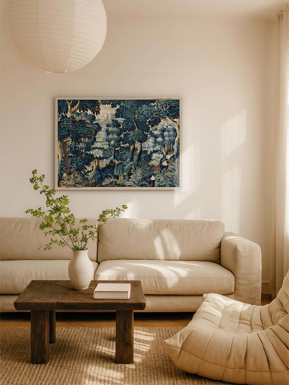 Großformatiger Verdure-Kunstdruck mit dichter Waldlandschaft in tiefen Blau- und Grüntönen hängt über einem hellen Sofa in einem ruhigen Wohnzimmer und schafft eine elegante, historische Atmosphäre mit textilem Charakter und klassischem Wandbild-Stil.