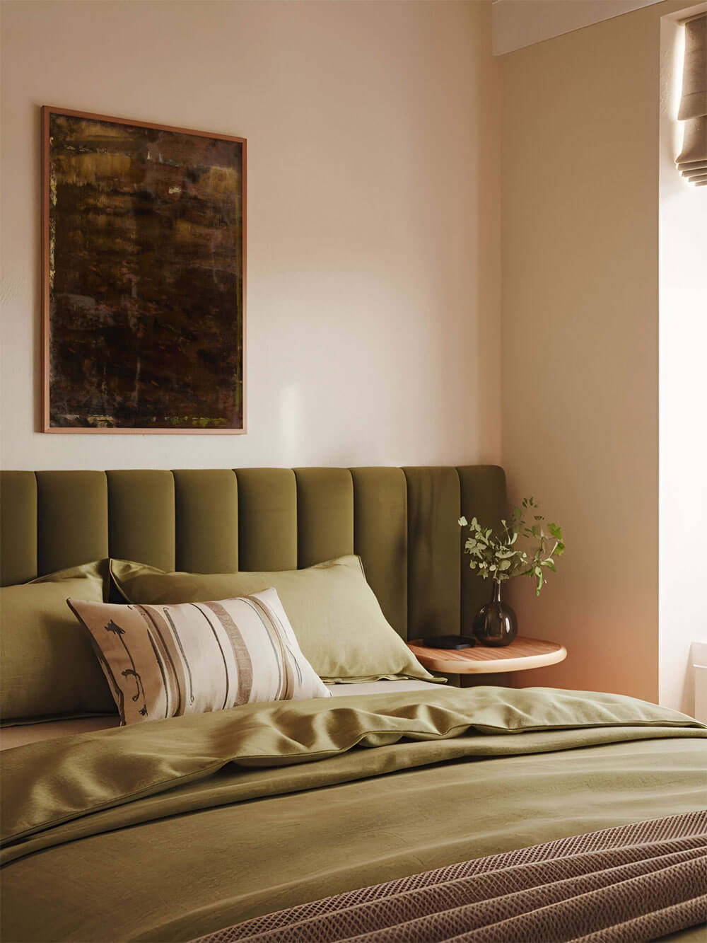 Dunkles abstraktes Poster über einem Bett mit grüner Bettwäsche im Schlafzimmer. Das Kunstwerk in Brauntönen mit goldenen Akzenten harmoniert mit der Natur-inspirierten Einrichtung und schafft eine beruhigende, warme Atmosphäre.
