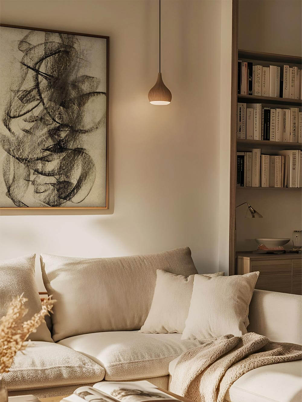 Großformatiger Kunstdruck mit ausdrucksstarken, schwarzen Linien auf texturiertem Papier hängt über einem cremefarbenen Sofa und wirkt wie ein meditatives Stillleben.