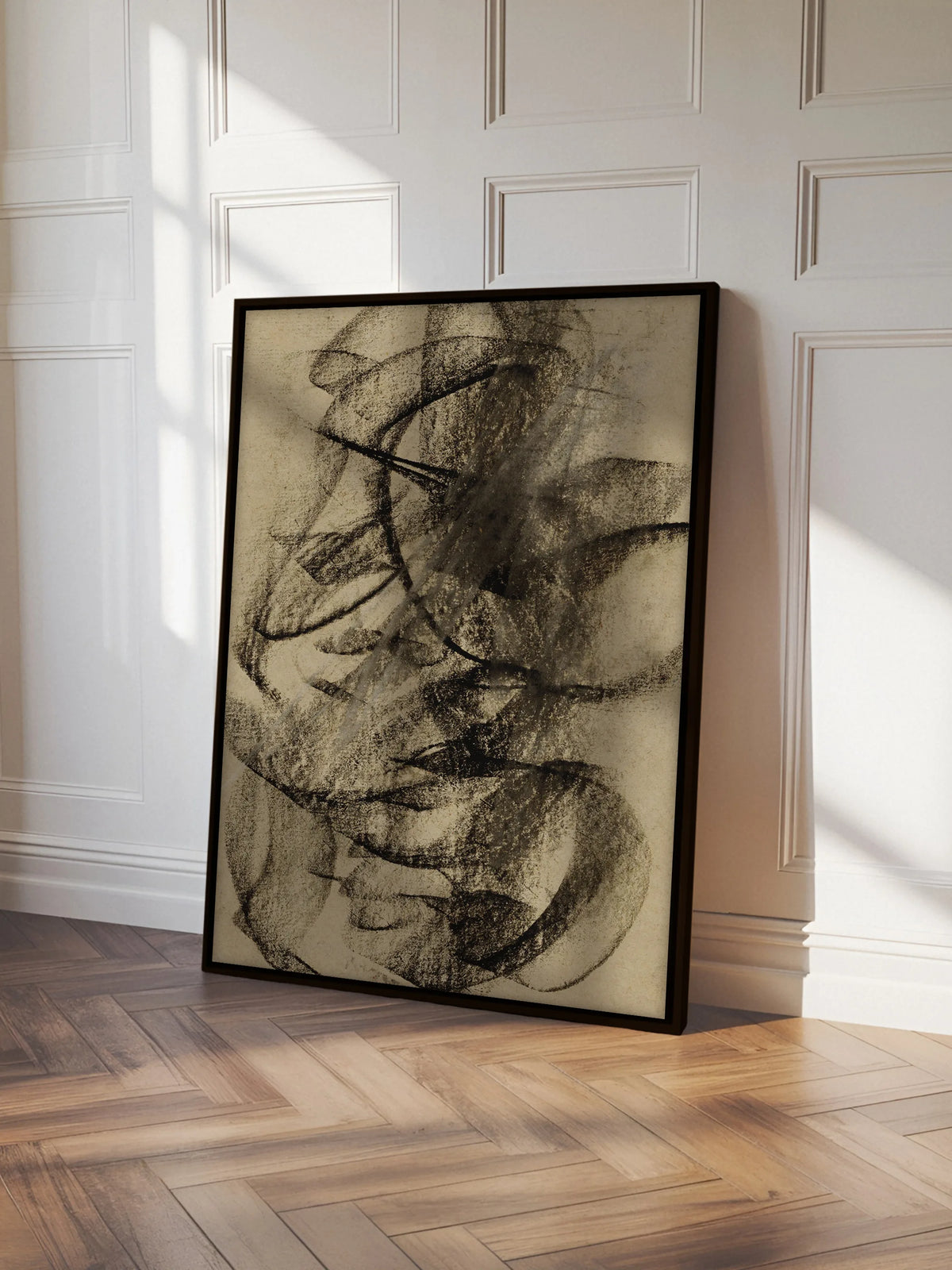 Abstraktes Leinwandbild im schwarzen Rahmen lehnt an einer weißen Kassettenwand auf Fischgrätparkett. Im Sonnenlicht treten die schwarzen Kreidelinien des Wabi Sabi Wandbilds deutlich hervor.