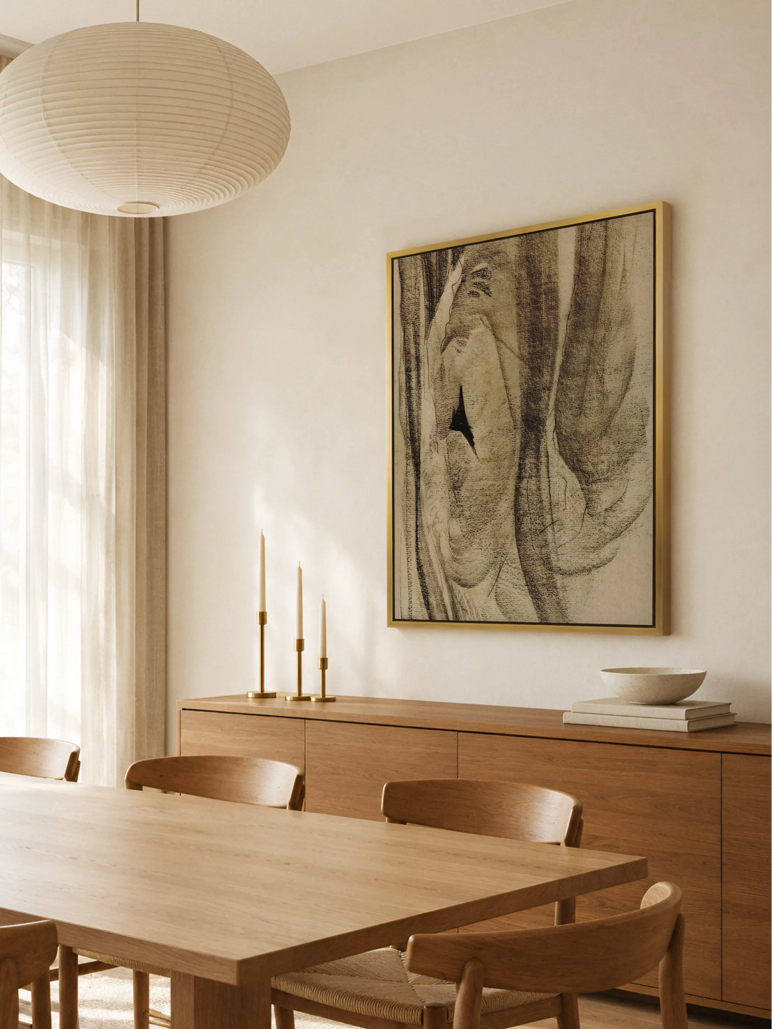 Abstraktes Leinwandbild im Goldrahmen über einem Sideboard aus warmem Holz mit Messingkerzenhaltern, davor ein Esstisch mit Holzstühlen und eine Papierleuchte. Das Wabi Sabi Wandbild passt zu den warmen Holztönen.