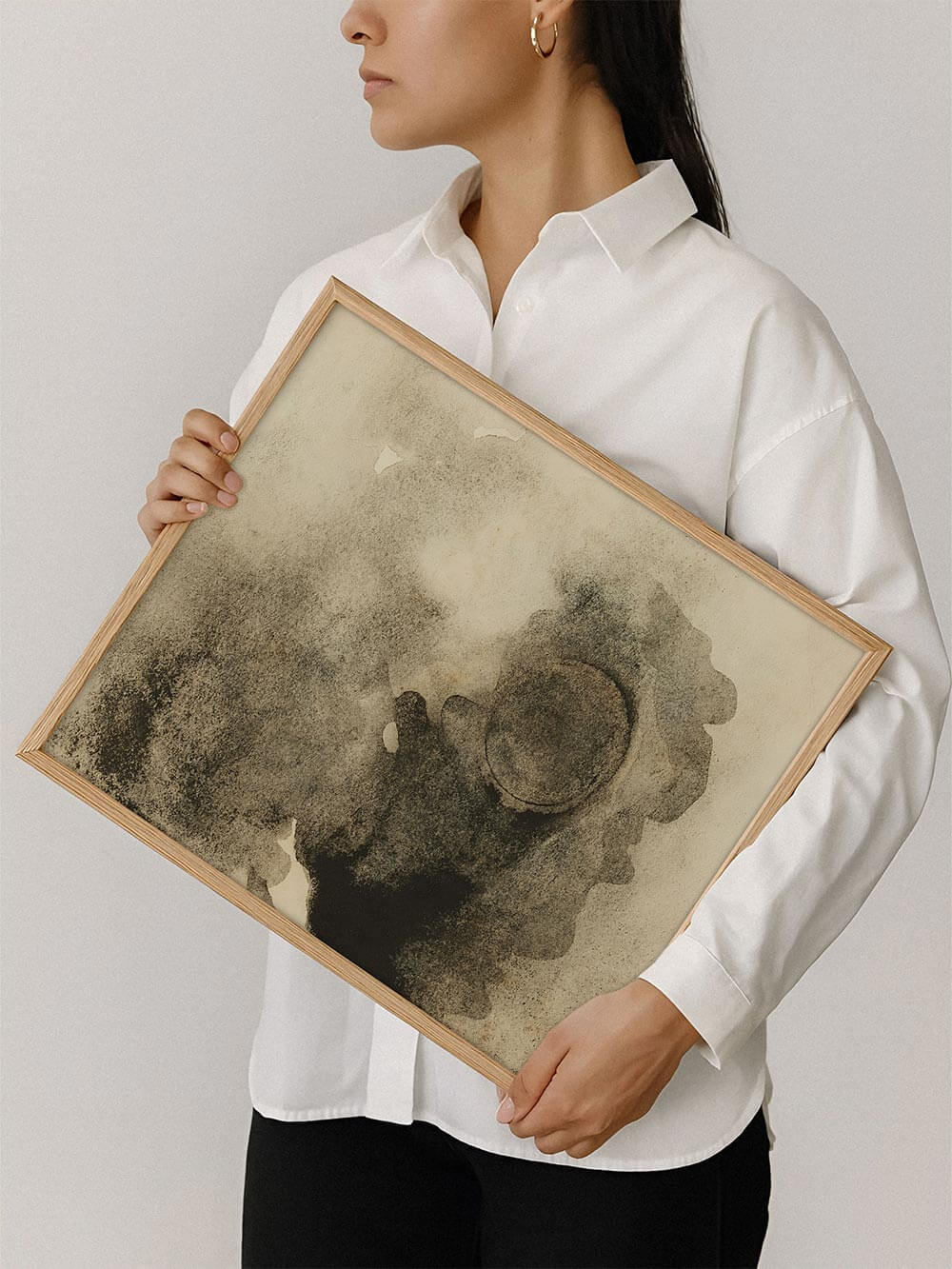 Gerahmter abstrakter Kunstdruck wird von einer Person gehalten und zeigt die harmonische Farbfläche aus Beige, Grau und Schwarz. Das Motiv vermittelt die Größe des Posters und eignet sich als modernes Wandbild für Wohnzimmer oder Atelier.