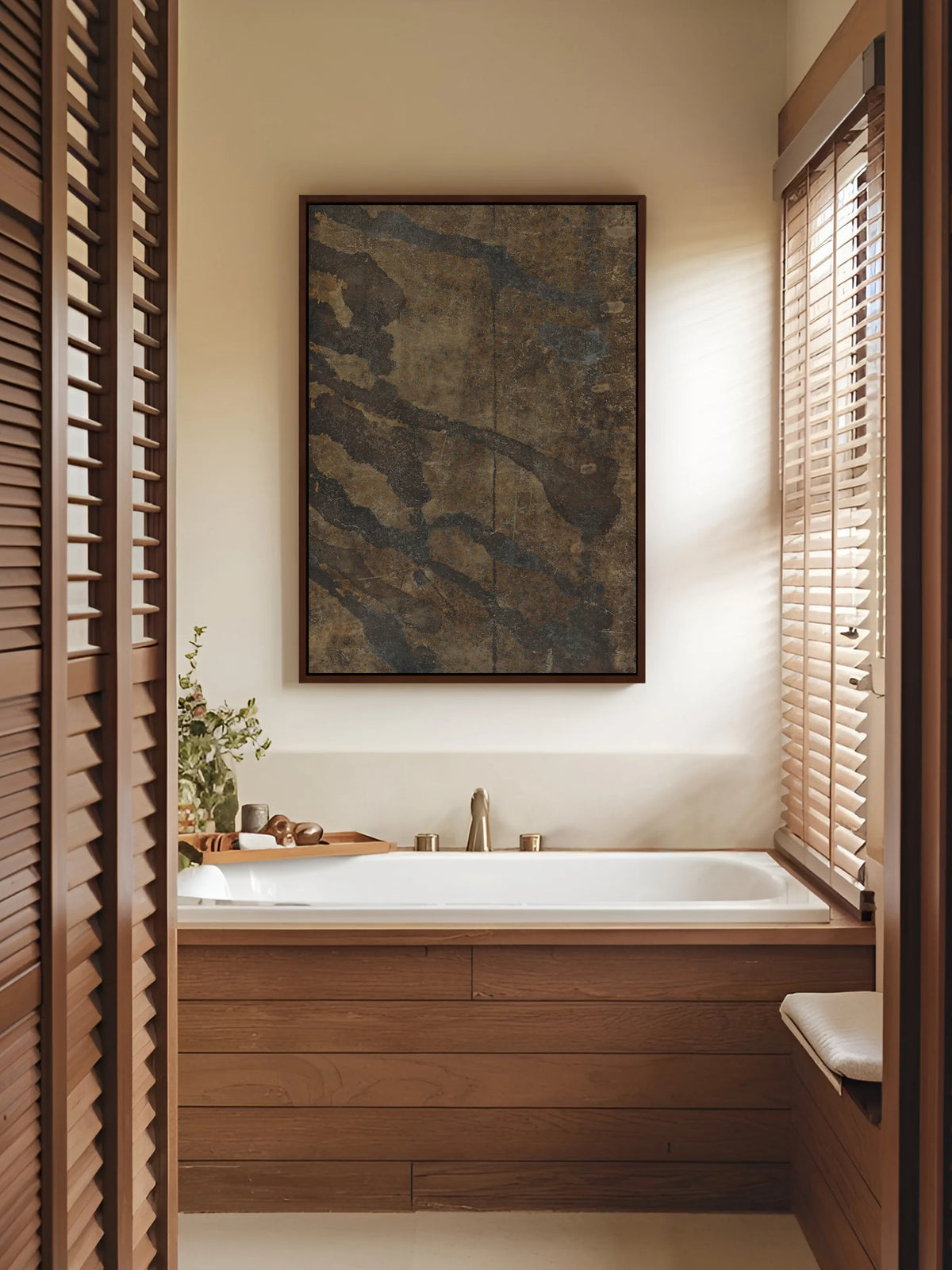 Wabi Sabi Leinwandbild in Erdtönen im braunen Rahmen über einer Badewanne mit Holzverkleidung, daneben Fensterläden und Jalousie aus Holz