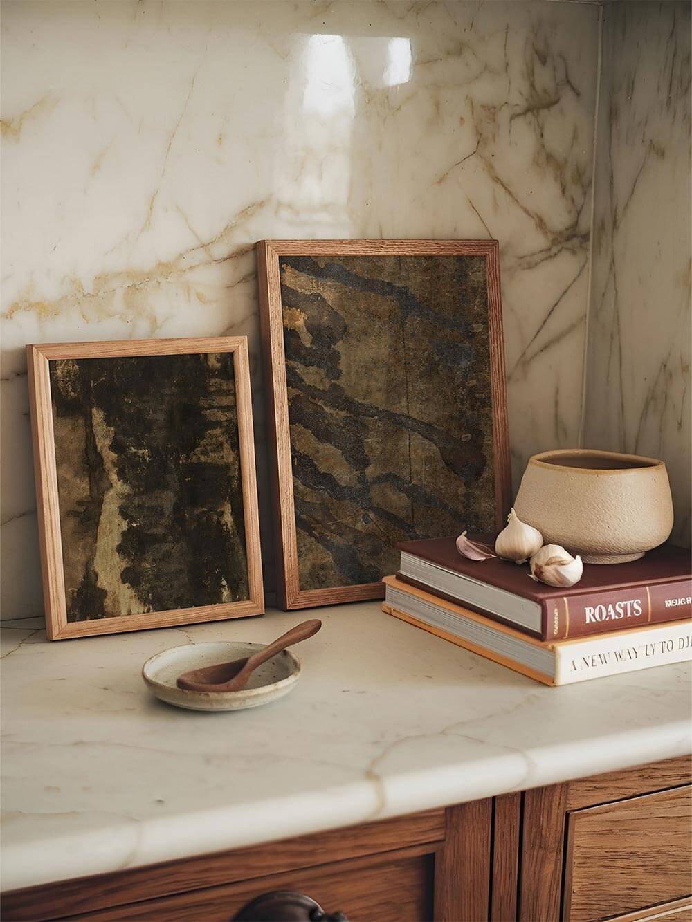 Abstrakter Wabi-Sabi Kunstdruck in erdigen Braun- und Grautönen, lässig gerahmt auf einer hellen Marmorarbeitsfläche arrangiert. Das Wandbild ergänzt die ruhige Küchenszene mit natürlicher Textur und wirkt als zurückhaltendes Poster für moderne Wohnküchen.