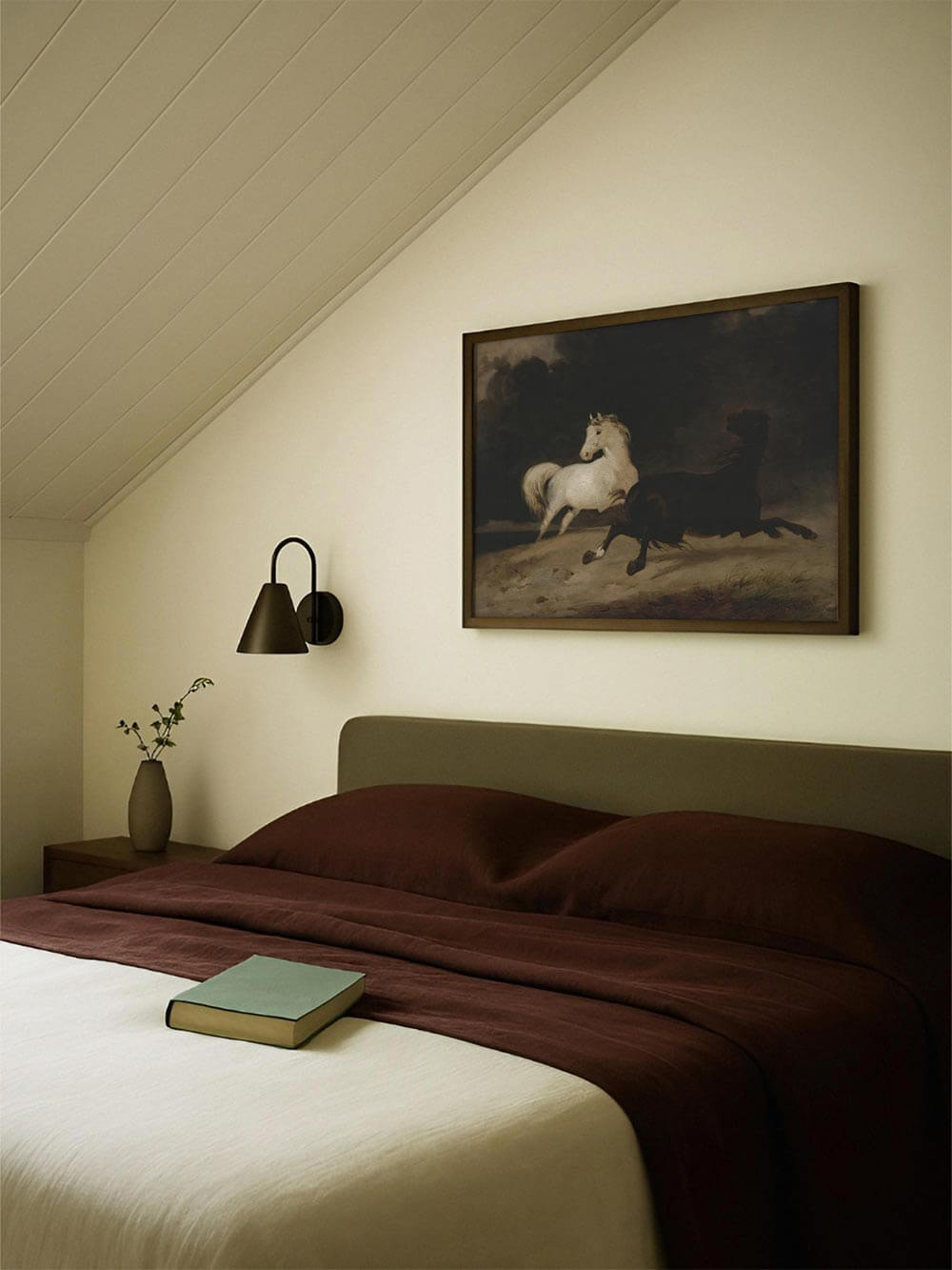 Vintage Kunstdruck mit zwei galoppierenden Pferden über einem Bett in ruhigem Schlafzimmer. Dunkle, dramatische Farbpalette und weiche Lichtstimmung schaffen eine elegante, klassische Atmosphäre für ein stilvolles Wandbild im Schlafzimmer.