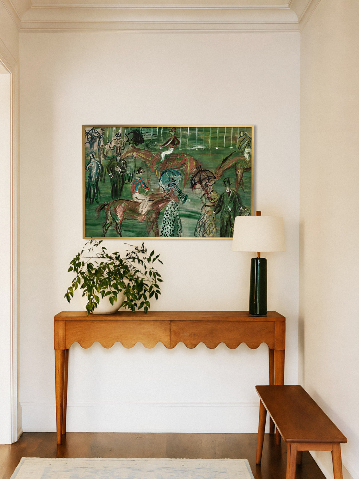 Vintage Pferderennen Kunstdruck im goldenen Rahmen über einer Holzkonsole mit Wellenkante im Flur, daneben eine grüne Tischlampe und eine Pflanze im weißen Topf. Das Poster bringt Farbe und Bewegung in einen hellen Eingangsbereich.