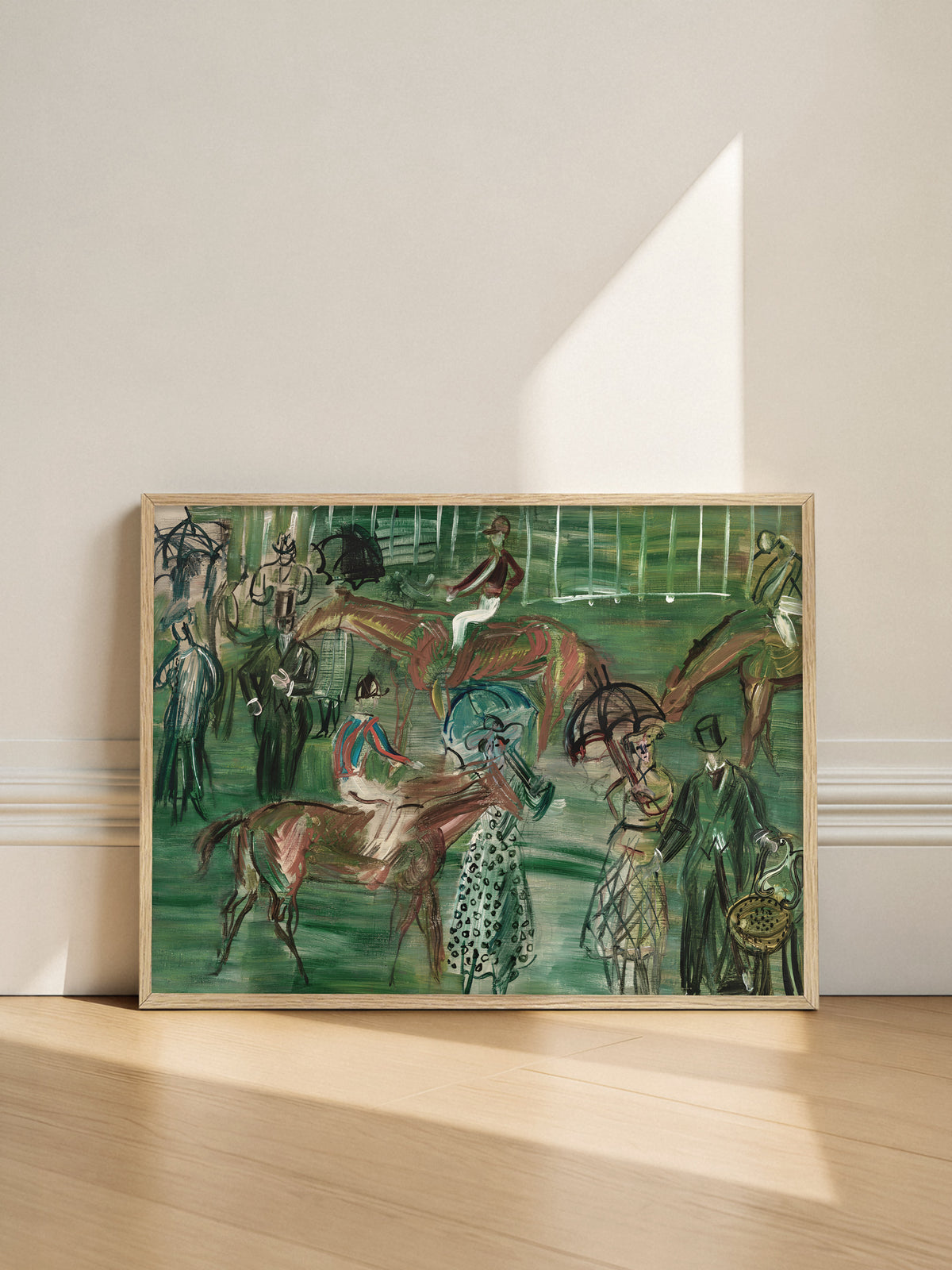Kunstdruck mit Pferderennen im hellen Holzrahmen, angelehnt an eine helle Wand auf einem Holzboden, während ein Lichtstreifen schräg auf die Wand fällt. Das grüne Vintage Pferde Poster bringt Bewegung in eine schlichte Einrichtung.