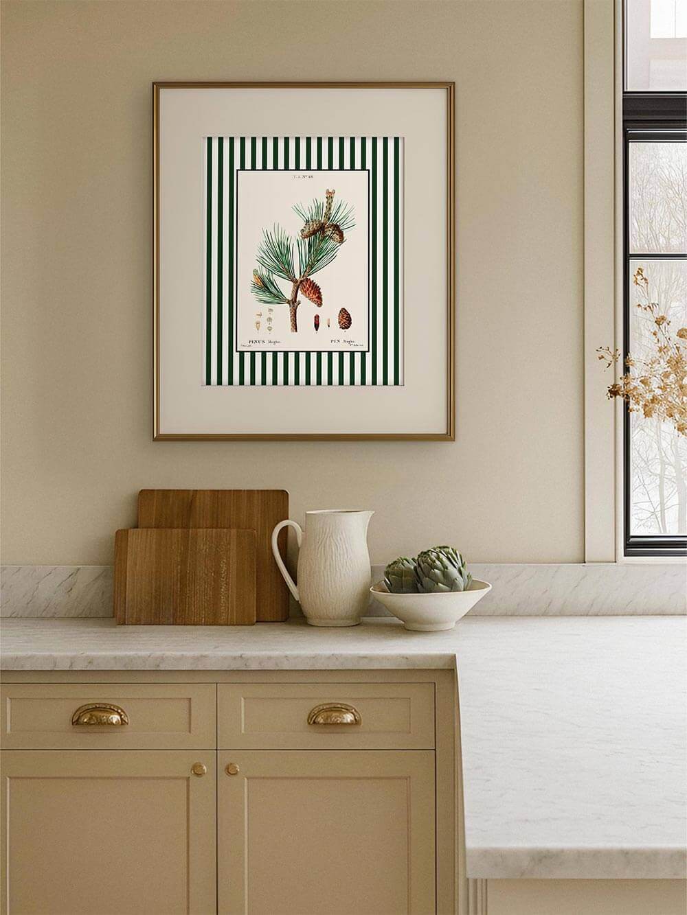 Botanischer Kunstdruck mit Kiefernzweig und rötlichen Zapfen über heller Marmorarbeitsplatte, eingerahmt in Holzrahmen, elegante Küche mit natürlichen Farbtönen.