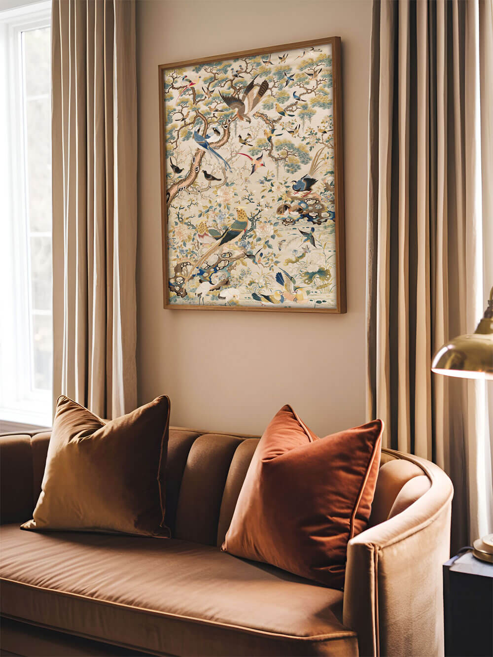 Antiker Chinoiserie-Kunstdruck mit Vögeln und Blumen an einer cremefarbenen Wand über einem samtigen Sofa mit dekorativen Kissen.
