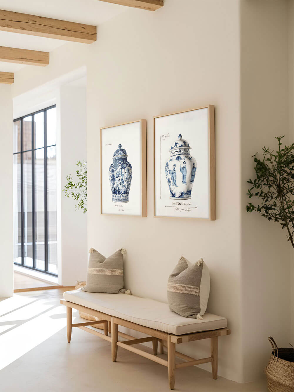 Set aus zwei blauen und weißen Vintage Chinoiserie Vasen Kunstdrucken, die nebeneinander in einem hellen Flur mit Holzbank und Kissen aufgehängt sind.