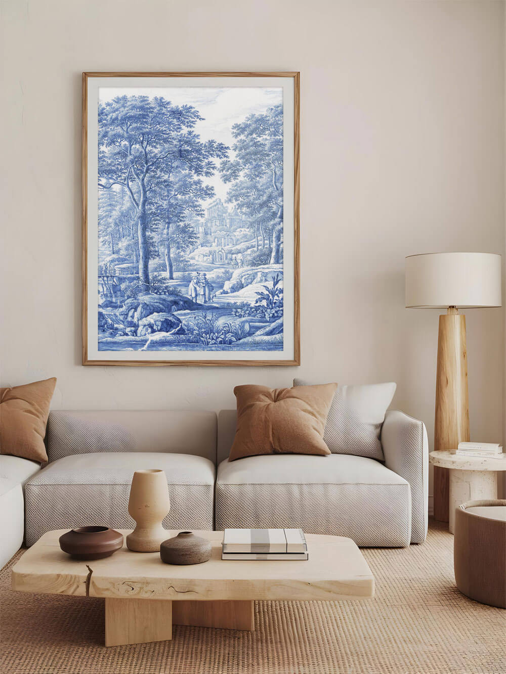 Ein großer blau-weißer Kunstdruck einer idyllischen Landschaftsszene hängt in einem modernen, minimalistisch eingerichteten Wohnzimmer. Der Kunstdruck zeigt Bäume, einen Fluss und eine alte Steinbrücke. Die Möbel im Raum sind in hellen, neutralen Tönen gehalten, was dem Raum eine warme und einladende Atmosphäre verleiht.