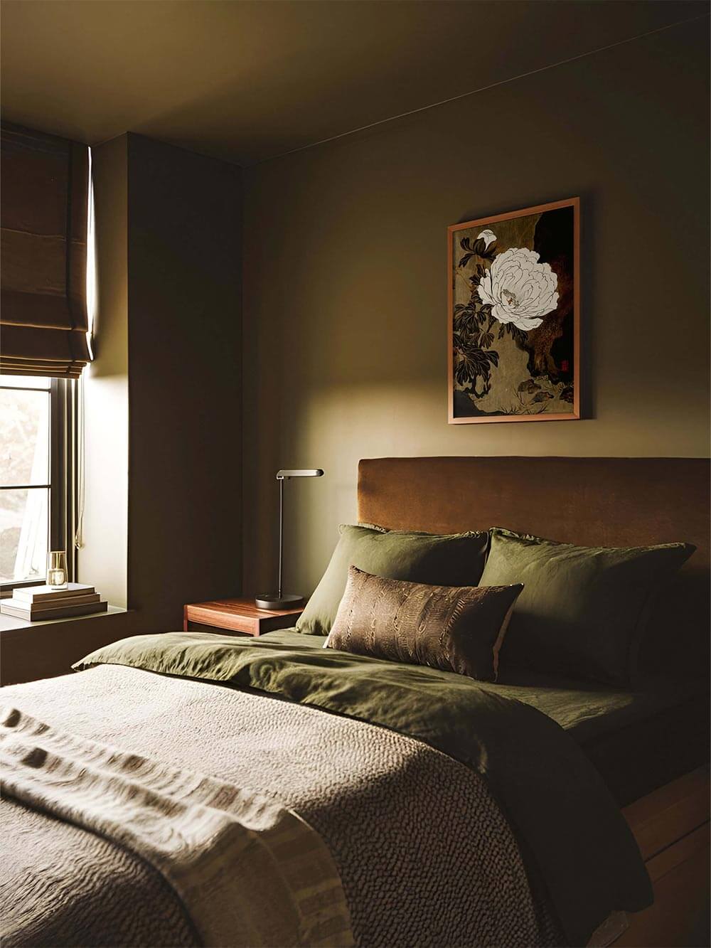 Gerahmtes Blumenbild mit Pfingstrose hängt über einem moosgrünen Bett in einem gedämpft beleuchteten Raum. Das Vintage-Wandbild fügt sich harmonisch in die beruhigende Schlafzimmeratmosphäre ein.