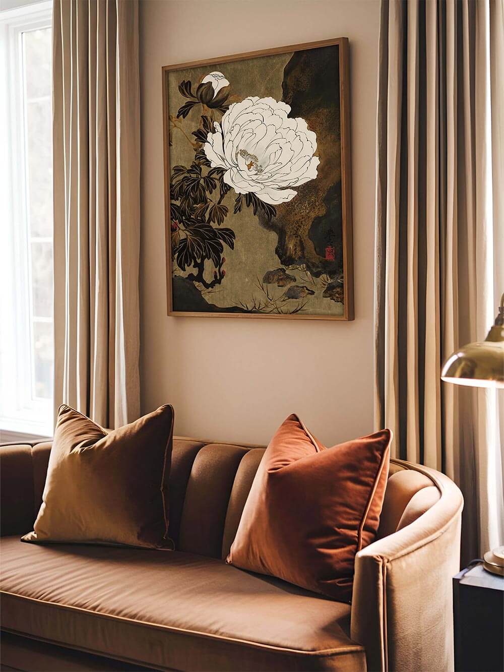 Pfingstrosen-Kunstdruck im Holzrahmen über einem samtigen Sofa in warmen Erdtönen. Das Vintage-Blumenbild bringt ruhige Eleganz und zeitlose Tiefe in das Wohnzimmer.