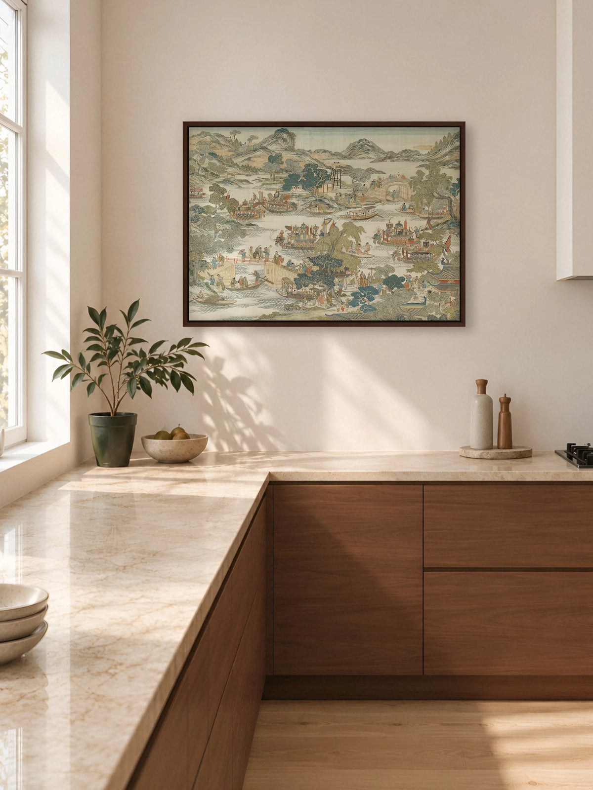 Leinwandbild mit asiatischer Flusslandschaft im braunen Rahmen an einer hellen Küchenwand über einer Arbeitsplatte aus beigem Marmor. Die Unterschränke aus Nussbaumholz greifen den Rahmen auf, daneben steht eine Topfpflanze.