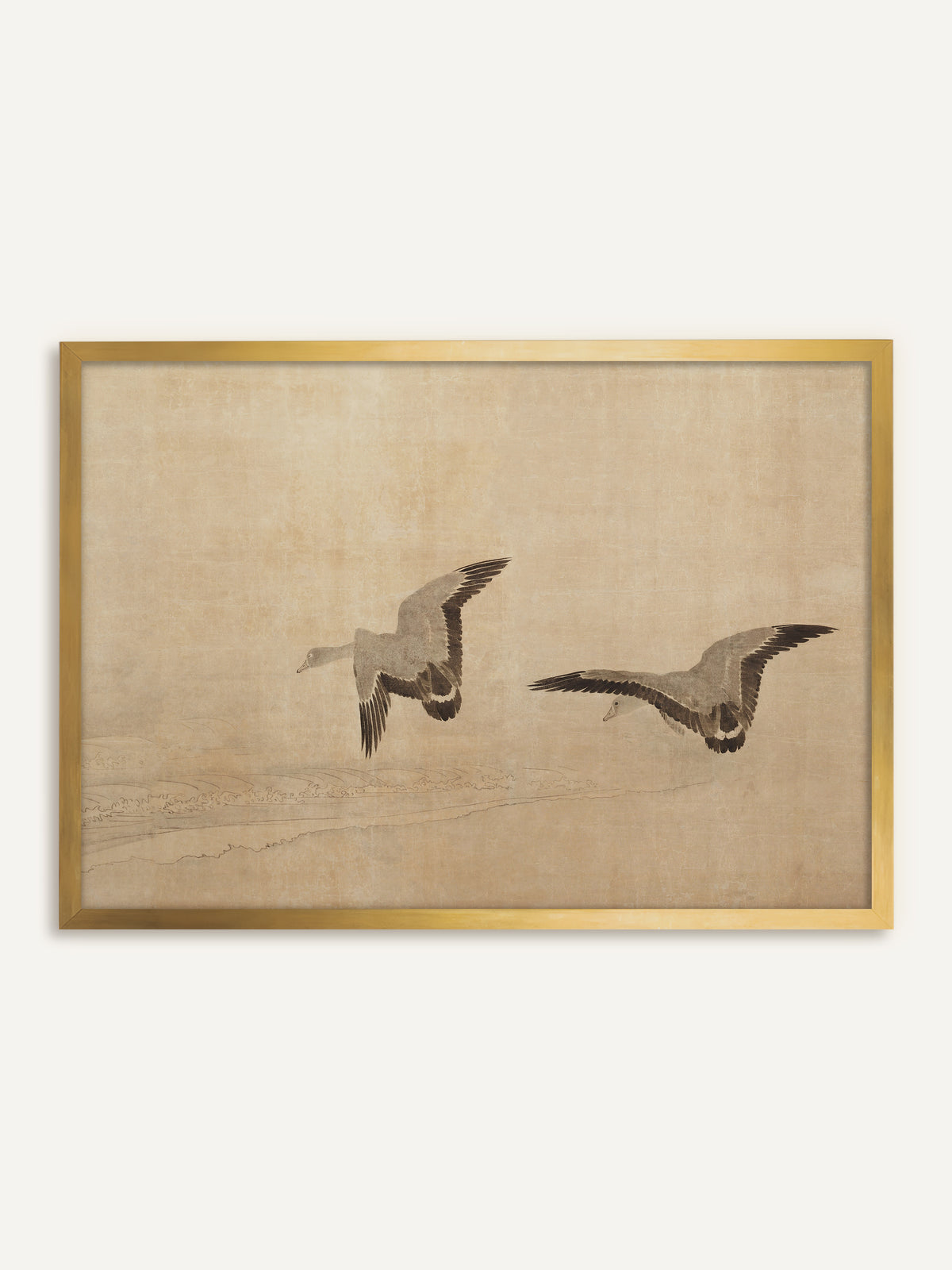 Wandbild, das zwei Gänse mit ausgebreiteten Schwingen in Grau und Braunschwarz zeigt, die über feine Wellenlinien an einem Strand fliegen, auf warmem, sandfarbenem Grund. Im goldenen Rahmen leuchtet der Sandton wärmer, und das Bild wirkt wie eine antike Tuschmalerei. #Rahmen_Gold