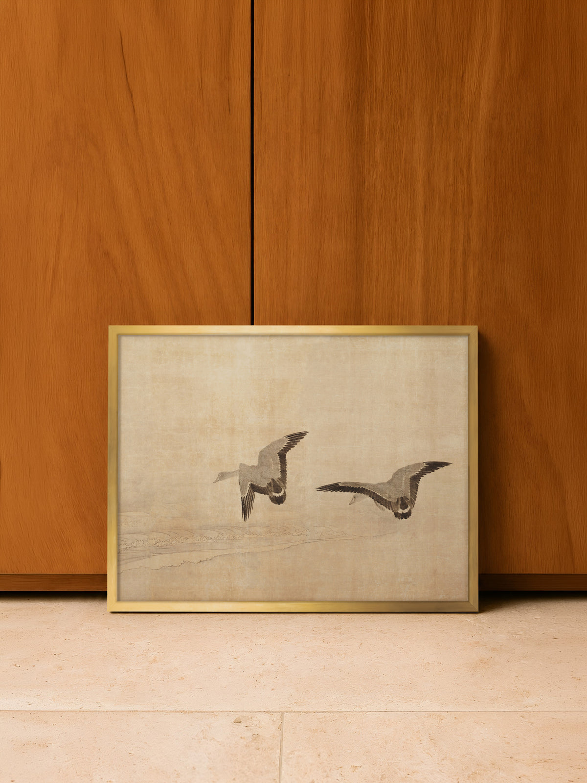 Kunstdruck mit fliegenden Gänsen im goldenen Rahmen, angelehnt auf hellem Steinboden vor Schranktüren aus warmem Holz. Die Beige- und Brauntöne des Vintage-Posters greifen die Farbe des Holzes auf.
