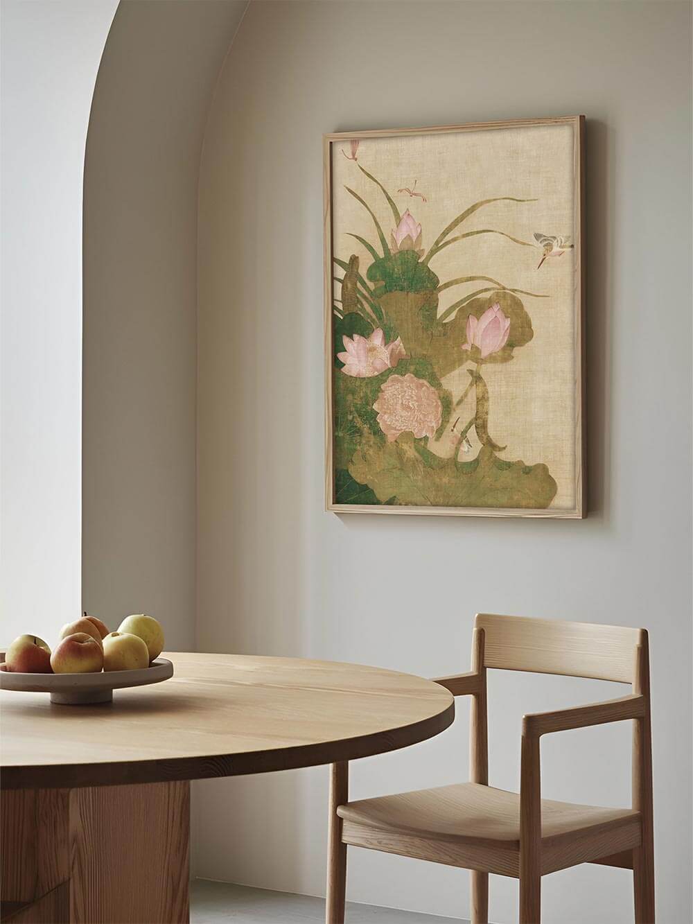 Der antike Blumen Kunstdruck mit Lotusblüten hängt über einem runden Holztisch im Esszimmer. Die zarten Farben und botanischen Motive schaffen ein ruhiges Ambiente.