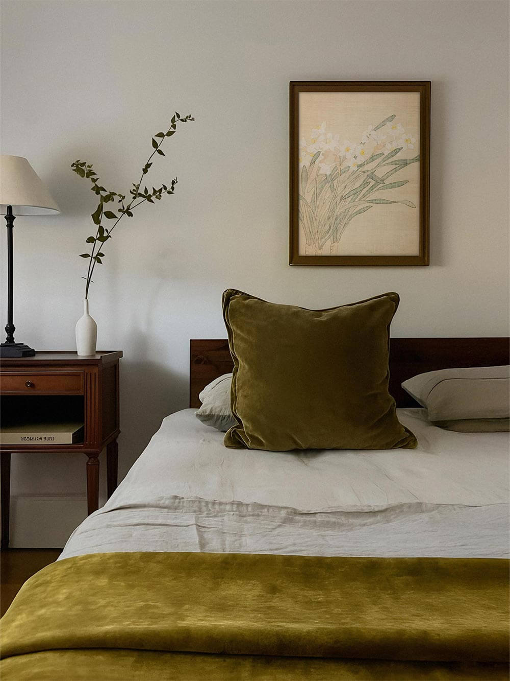 Der Vintage Narzissen Kunstdruck hängt gerahmt über einem Bett mit olivgrüner Bettwäsche. Die florale Illustration bringt Leichtigkeit und natürliche Harmonie in den Raum.