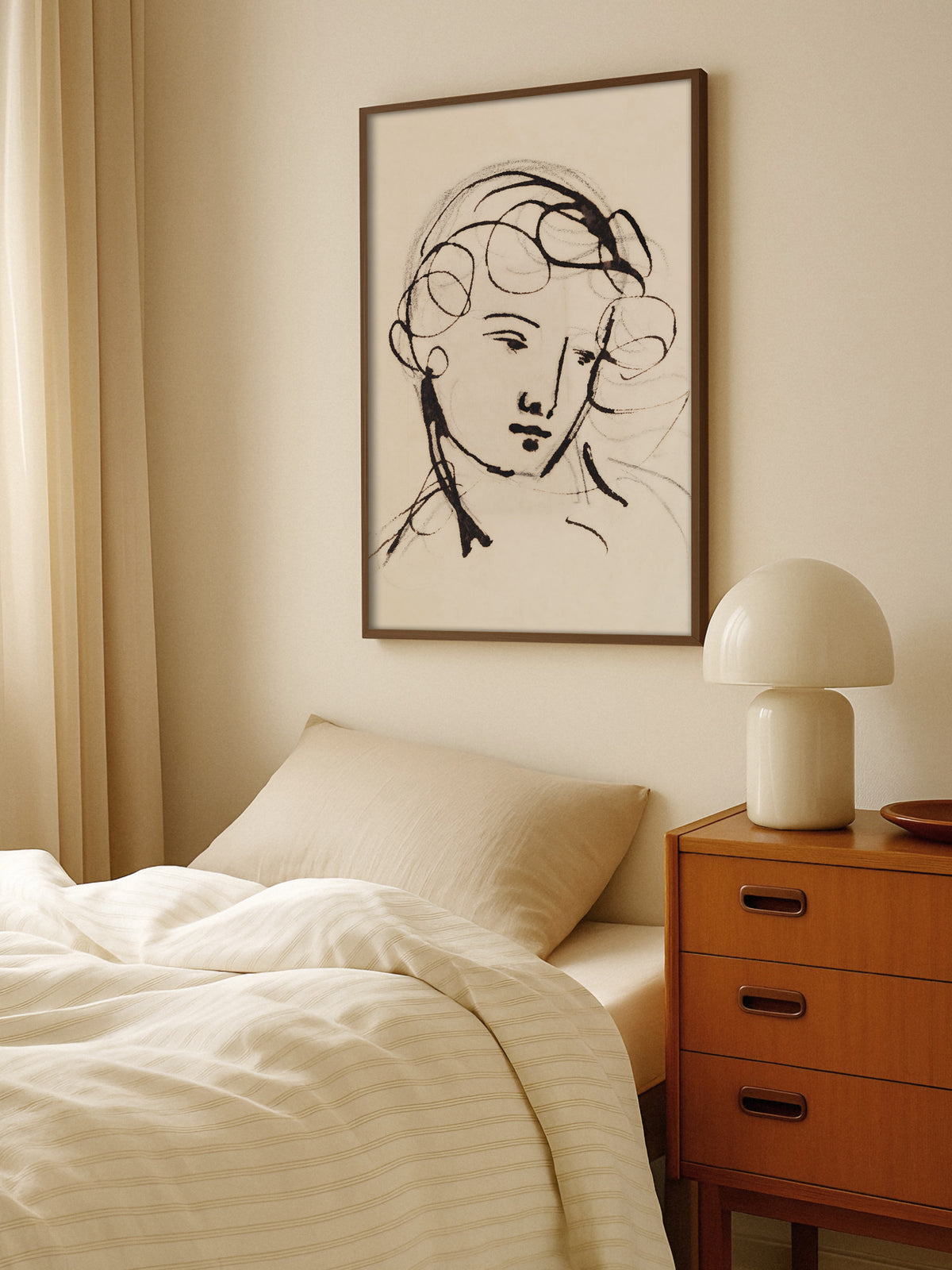 Kunstdruck mit minimalistischem Frauenporträt im Rahmen aus dunklem Holz über einem Bett mit heller Bettwäsche, daneben eine Holzkommode mit weißer Pilzlampe. Die Vintage Zeichnung fügt sich in das warme, beige Schlafzimmer ein.