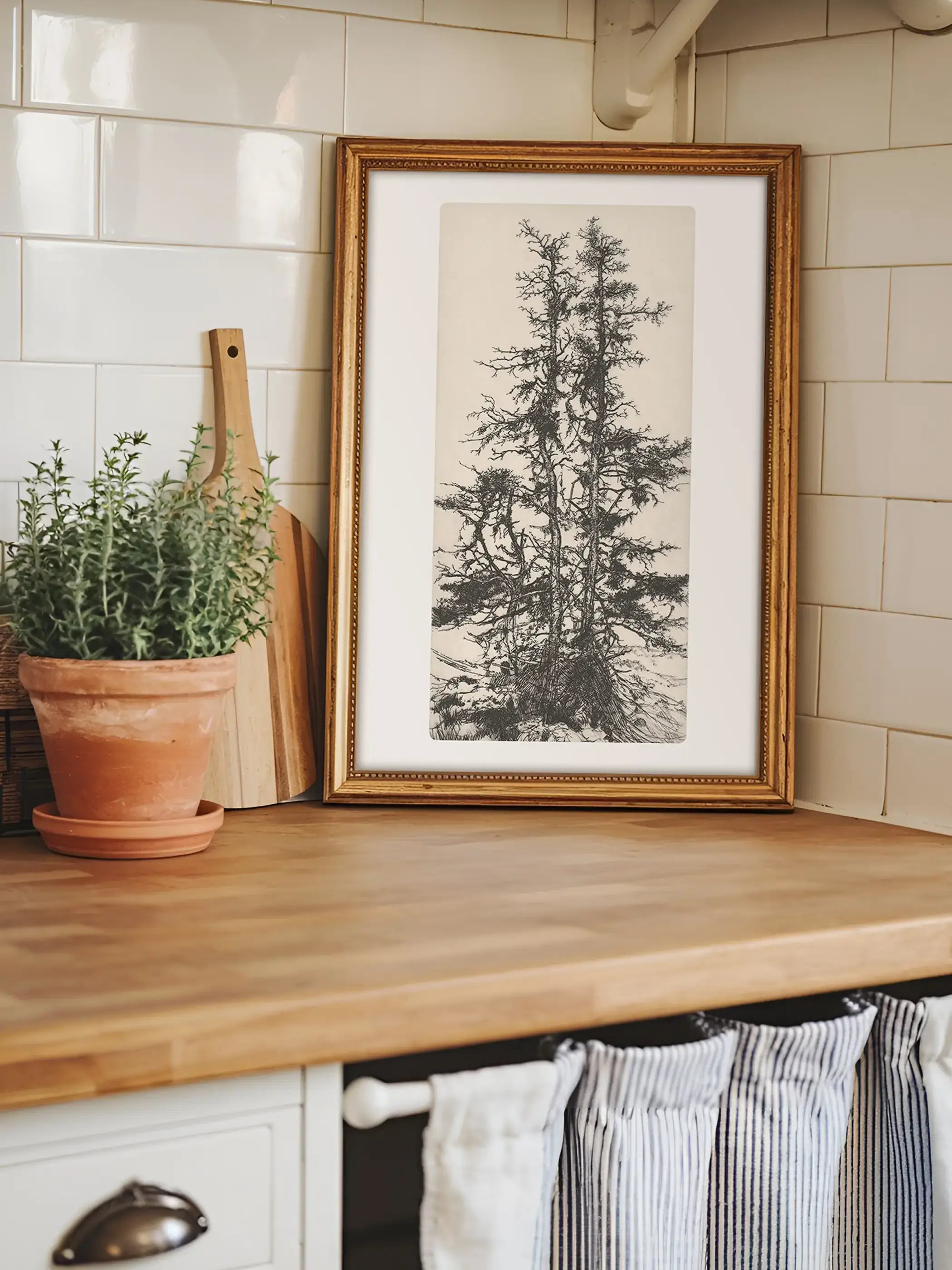 Der gerahmte Baumdruck lehnt auf einer Holzarbeitsplatte vor hellen Fliesen und sorgt für einen natürlichen Blickfang. Das botanische Wandbild ergänzt Landhausküchen, Wabi-Sabi und zeitlose Wohnkonzepte mit dezenter Eleganz.