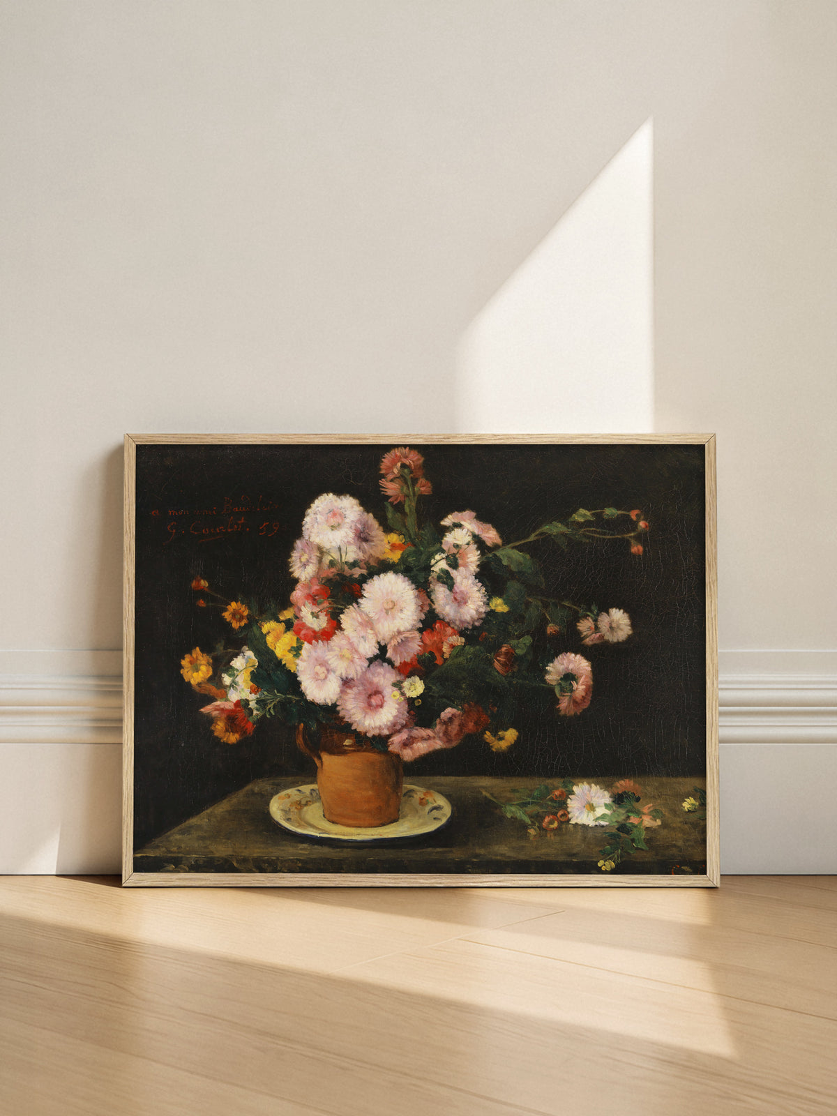 Kunstdruck mit Asternstrauß im hellen Holzrahmen, angelehnt an eine helle Wand auf einem Holzboden, während ein Lichtstreifen schräg auf die Wand fällt. Das Vintage Blumen Wandbild bringt Farbe in eine schlichte Einrichtung.