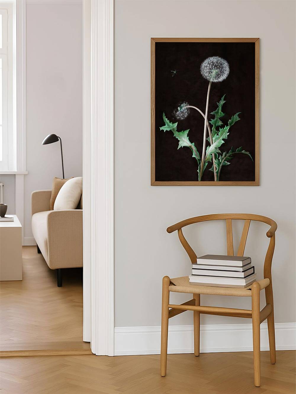 Botanisches Wandbild mit Löwenzahn in Naturtönen über einem Holzstuhl mit Büchern. Das Bild bringt eine stille, natürliche Note in den Raum.