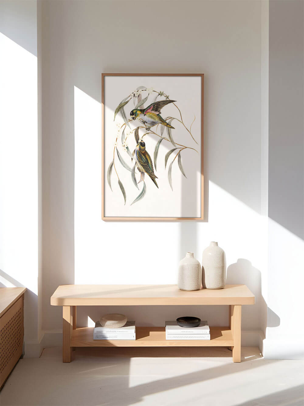 Vintage-Vogelillustration als gerahmter Kunstdruck in einem minimalistischen, hellen Raum, präsentiert über einer schlichten Holzbank mit Keramikvasen und Büchern.