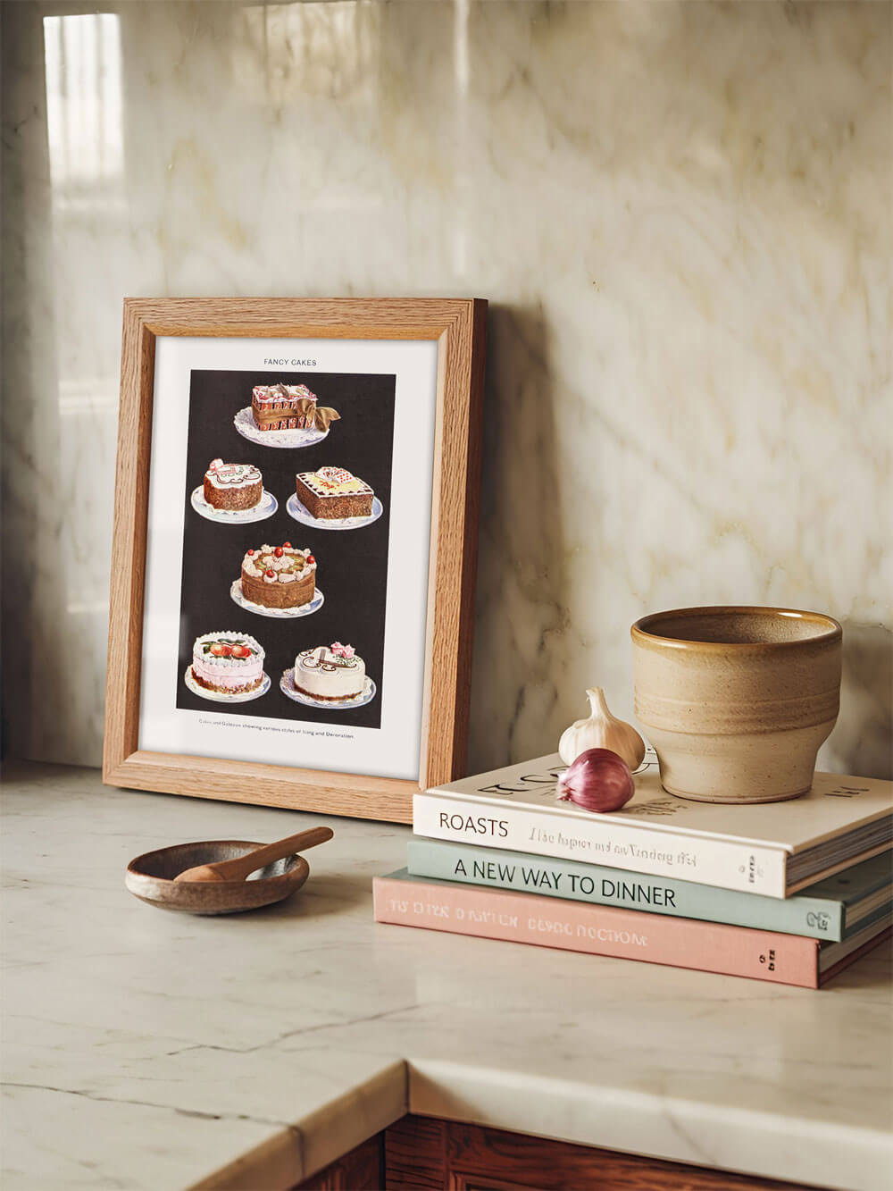 Gerahmter Retro-Kunstdruck mit Vintage-Kuchen, aufgestellt in einer Küche neben Kochbüchern und Keramik, dekoriert auf einer Marmoroberfläche.