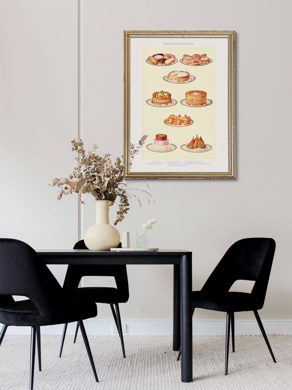 Vintage-Kunstdruck von Kuchen und Gebäck im goldenen Rahmen, an der Wand eines modernen Esszimmers mit schwarzem Tisch und heller Blumenvase.