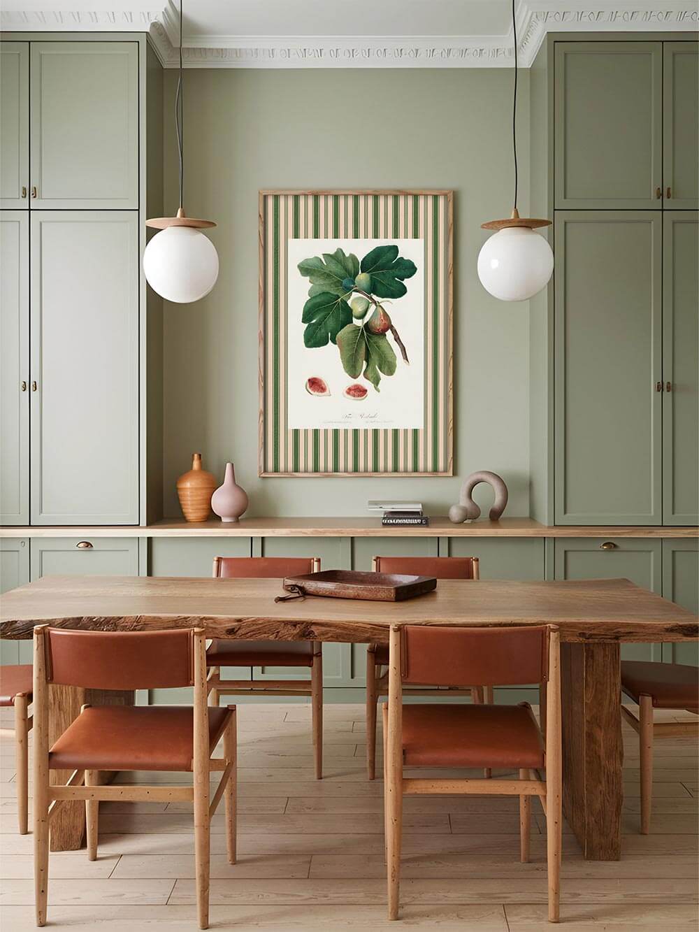 Vintage Feigenposter in Holzrahmen über einem Esstisch in einem hellgrünen Interieur. Das Wandbild ergänzt harmonisch den natürlichen Look der Küche.