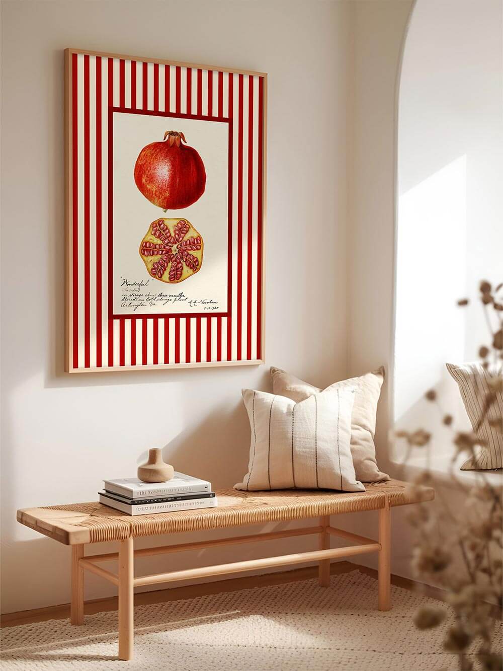 Granatapfel-Kunstdruck mit rot-beiger Streifenbordüre in heller Sitzecke mit Naturholzbank, neutralen Kissen und warmem Licht – inspiriert von Vintage-Küchenkunst und botanischer Illustration.