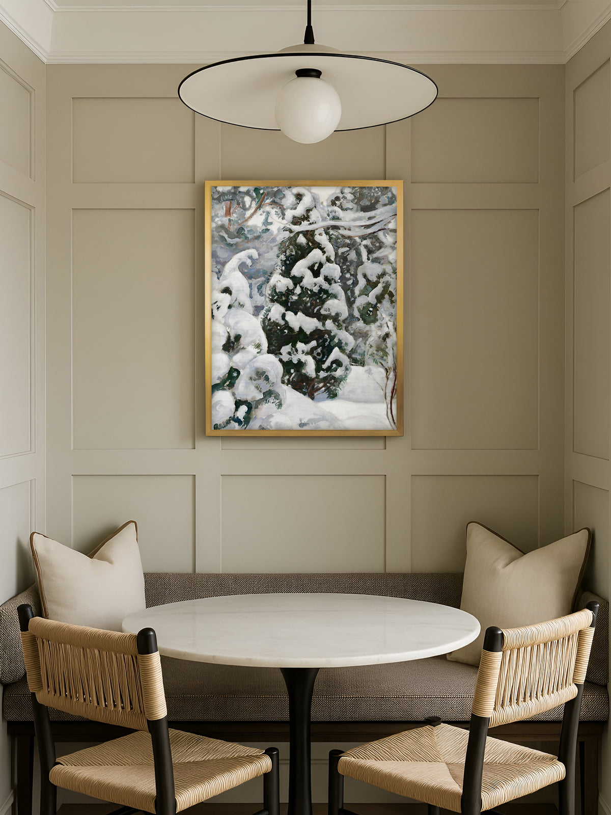 Japandi Wandbild mit Wacholder im Schnee im goldenen Rahmen über einer Sitzbank in der Essecke, davor ein runder Marmortisch mit Korbstühlen vor einer Kassettenwand.