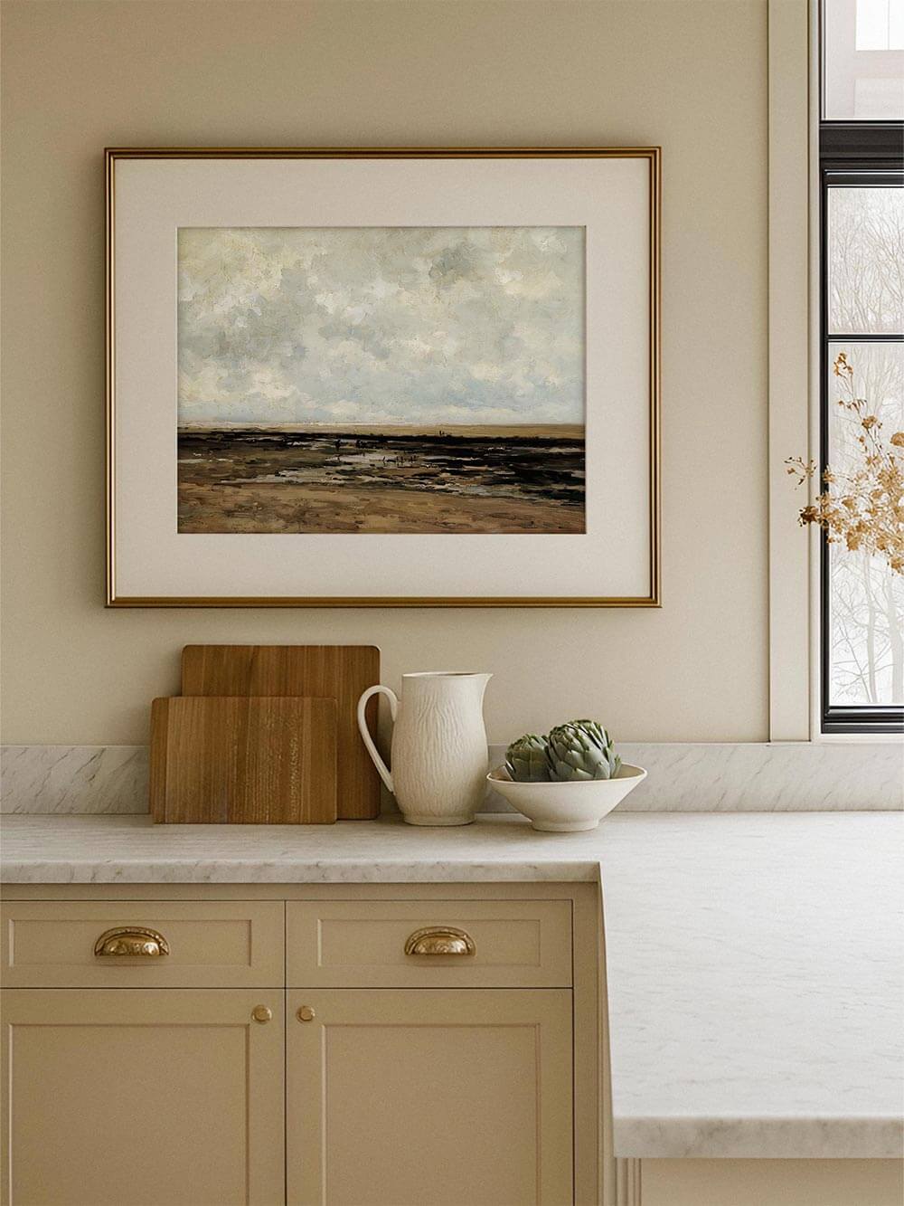 Gerahmter Landschafts-Kunstdruck mit weiter Küstenebene und hellem Himmel hängt über einer hellen Küchenarbeitsfläche mit Keramik und Holzaccessoires. Das ruhige Wandbild in Beige- und Grautönen ergänzt eine zeitlose Küche und wirkt harmonisch sowie zurückhaltend elegant.