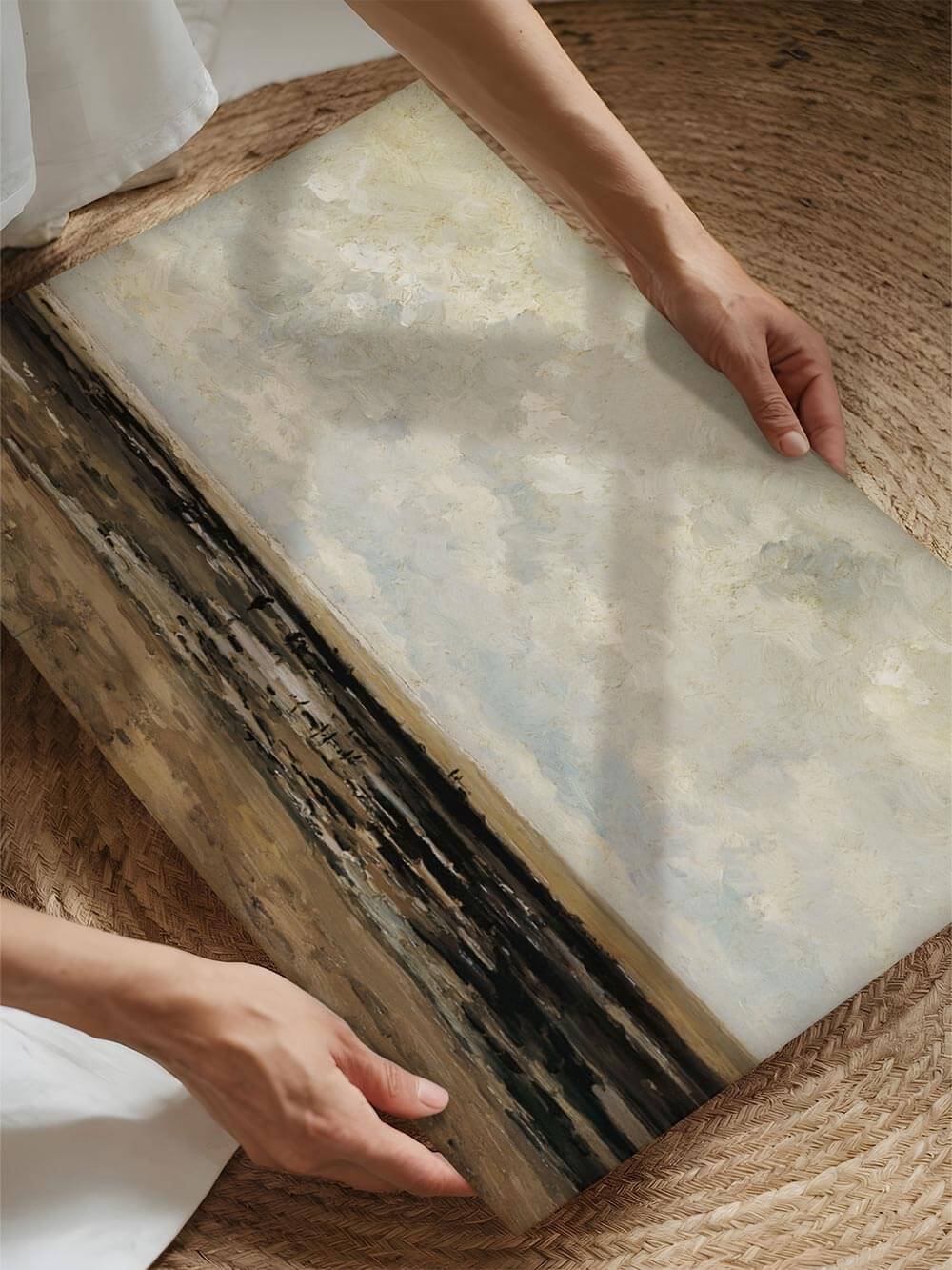 Kunstdruck mit abstrakt anmutender Küstenlandschaft wird vorsichtig in den Händen gehalten, wodurch Papierstruktur und matte Oberfläche sichtbar werden. Die Szene vermittelt Wertigkeit und eignet sich zur Darstellung von hochwertigem Wandbild und Kunstdruckqualität.