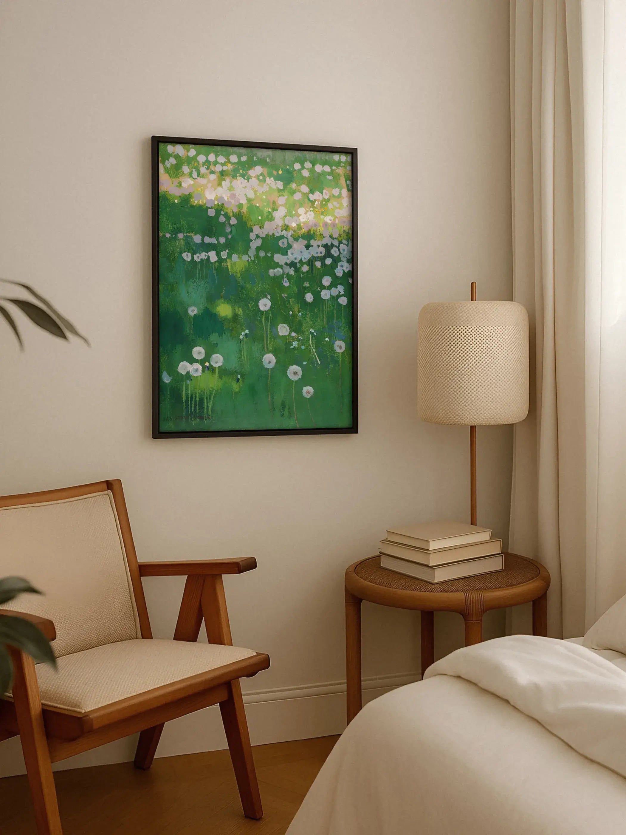 Kunstdruck mit Löwenzahnwiese in schwarzem Rahmen hängt über einem runden Beistelltisch neben einem hölzernen Sessel und einem Bett. Das grüne Wandbild bringt eine frische, naturnahe Note in die Sitzecke.