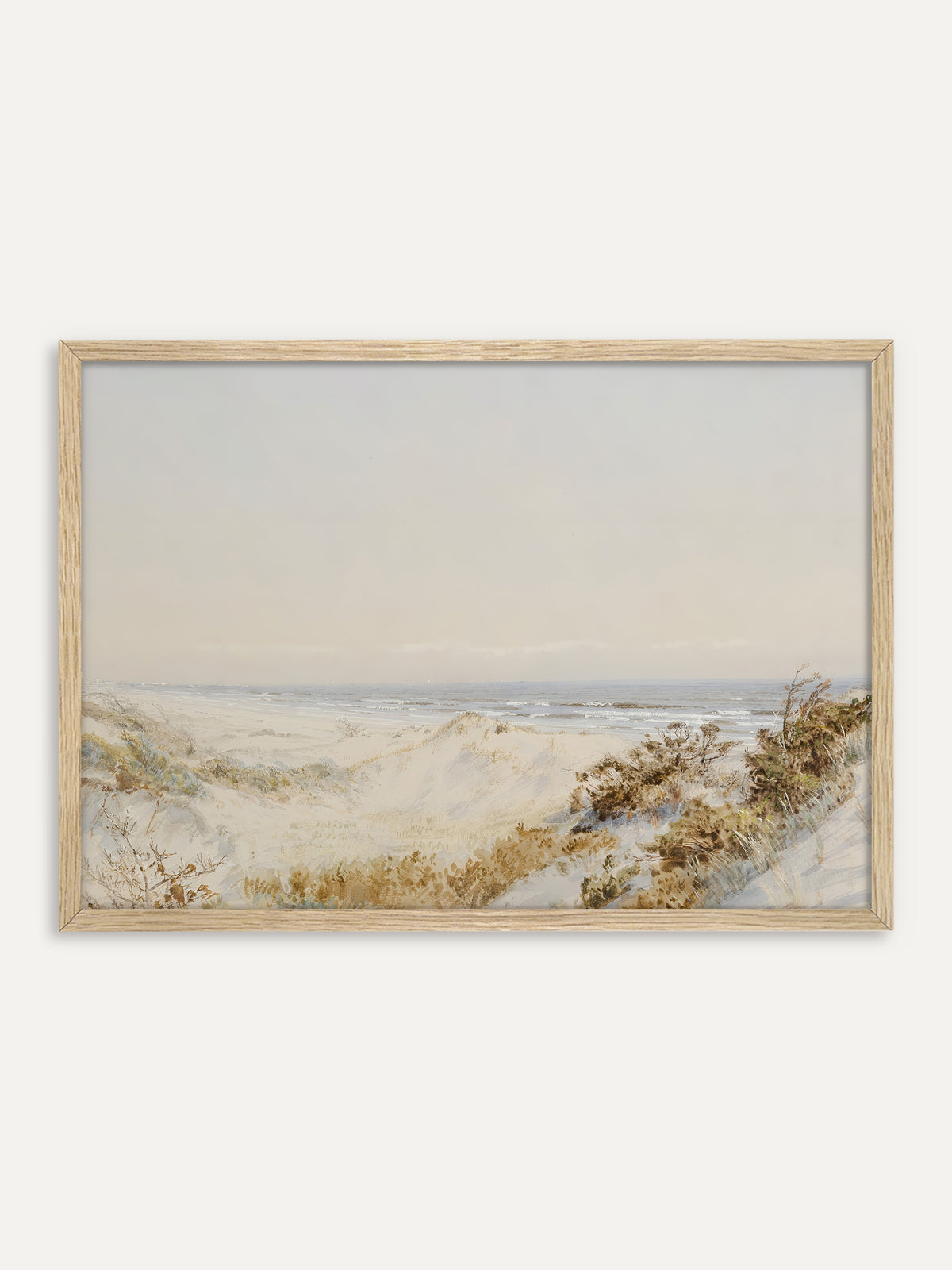 Kunstdruck, der sanfte Sanddünen mit trockenen Gräsern und Sträuchern zeigt, hinter denen das Meer mit kleinen weißen Wellen unter einem blassen Himmel liegt. Der helle Holzrahmen unterstreicht die natürliche Japandi Stimmung. #Rahmen_Helles Holz