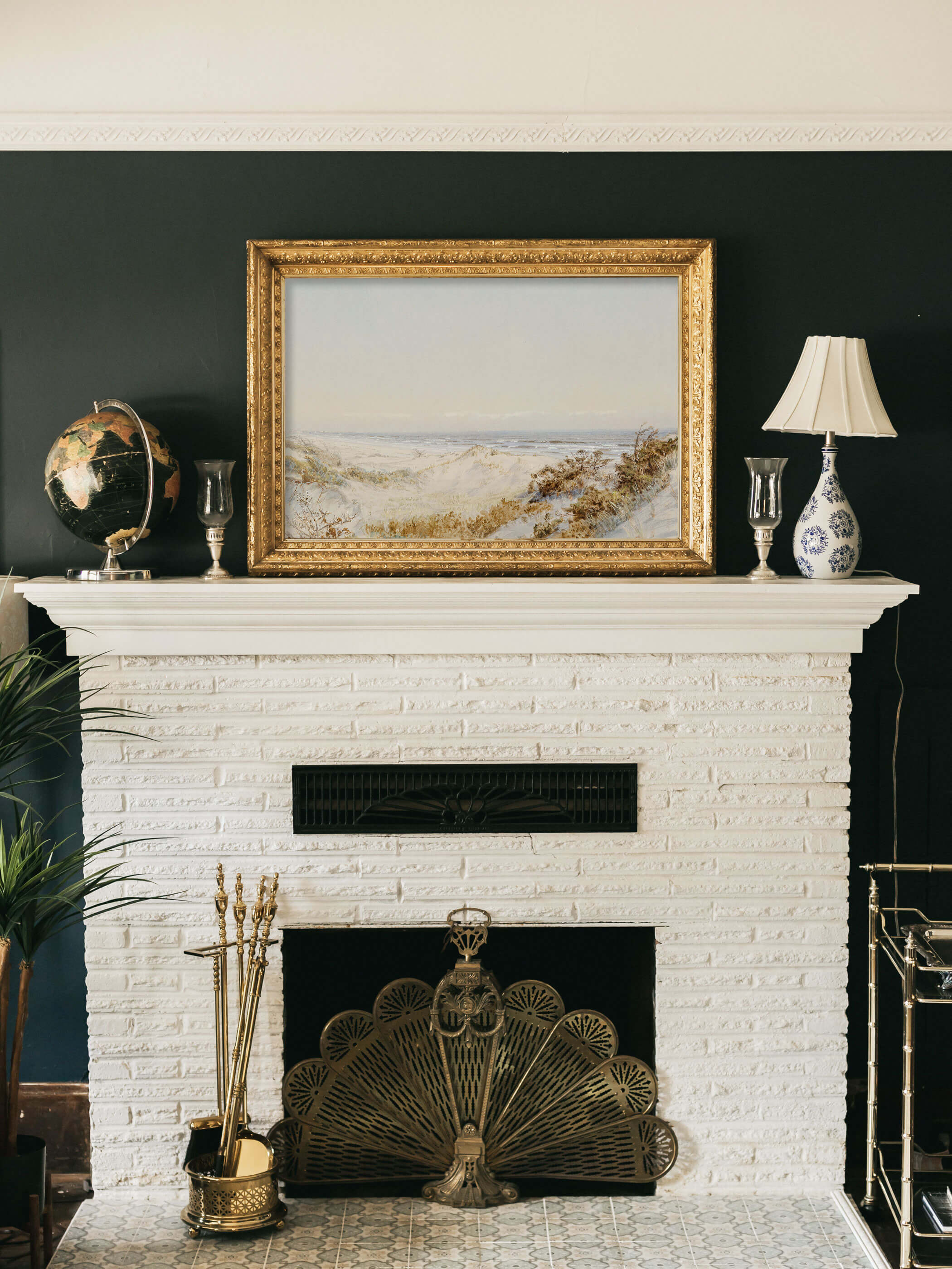 Vintage Kunstdruck von Dünen am Atlantik in einem goldenen Rahmen, stilvoll über einem Kamin mit weißer Backsteinwand und goldenen Dekorationen aufgehängt.