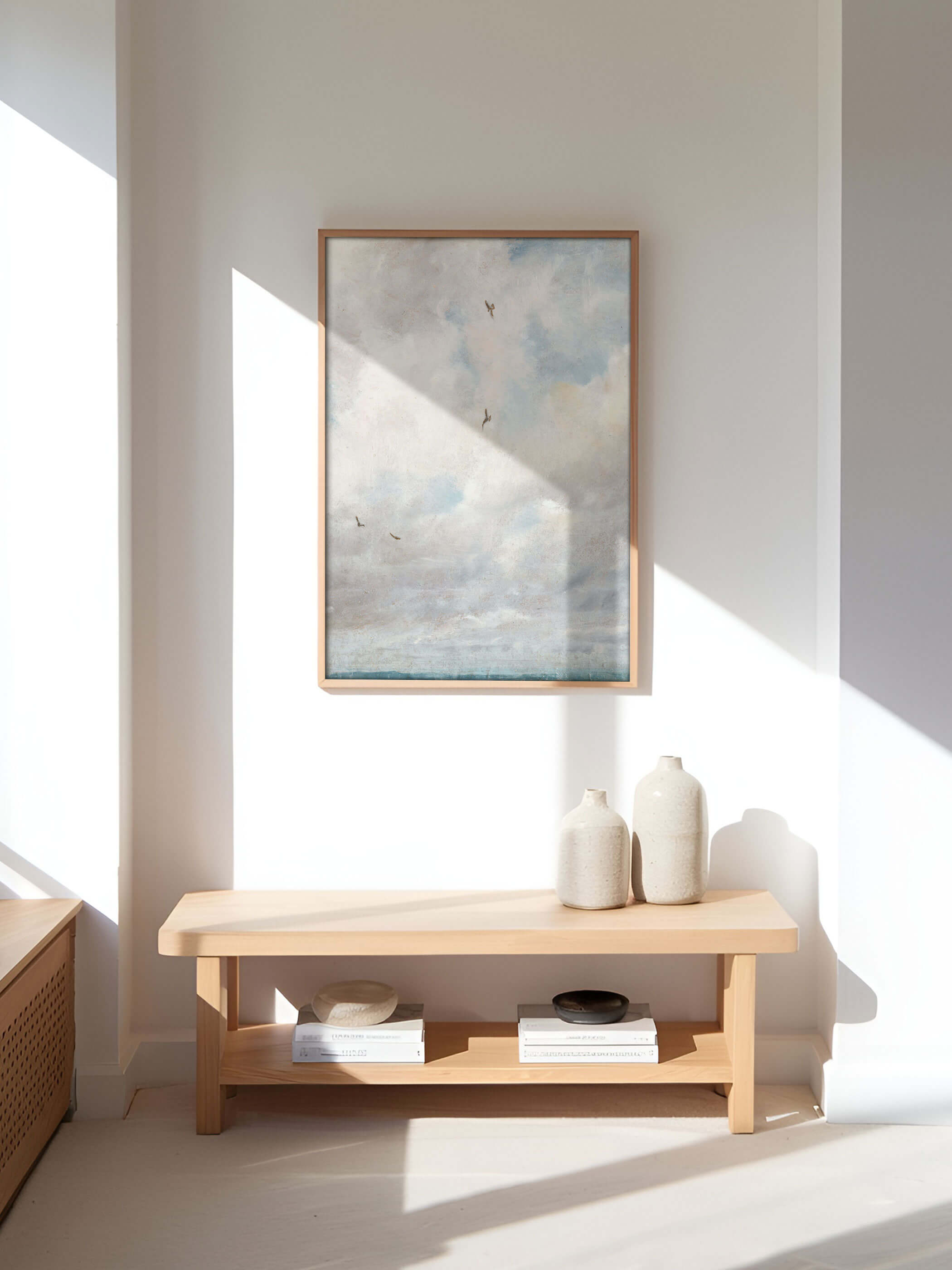 Minimalistisch eingerichteter Flur mit einem großen Vintage-Wolkenposter, das an der Wand hängt und von Sonnenlicht beschienen wird. Helle Möbel und Accessoires sorgen für ein harmonisches Gesamtbild.