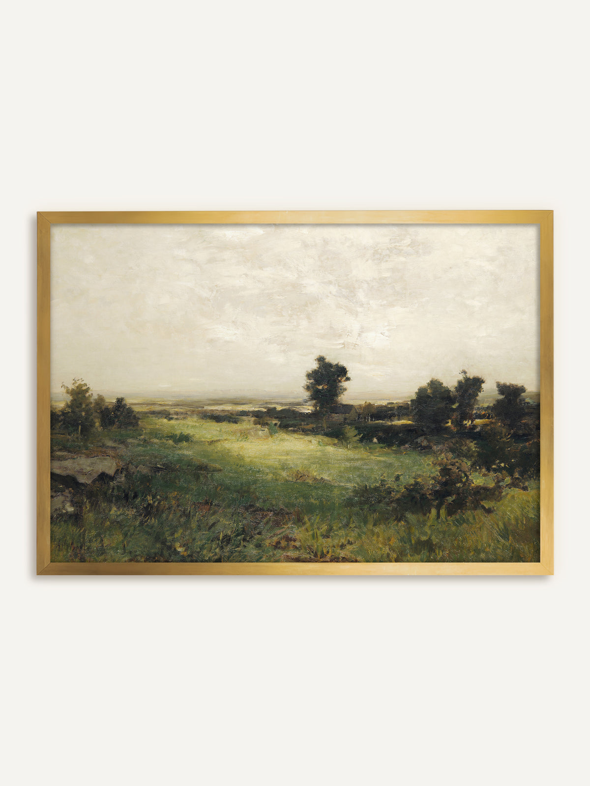 Wandbild, das eine weite grüne Wiese mit Felsen und dunklen Baumgruppen zeigt, dahinter ein flaches Tal unter einem hellen, cremeweißen Himmel. Im goldenen Rahmen bekommt das Motiv die Wirkung eines antiken Ölgemäldes. #Rahmen_Gold