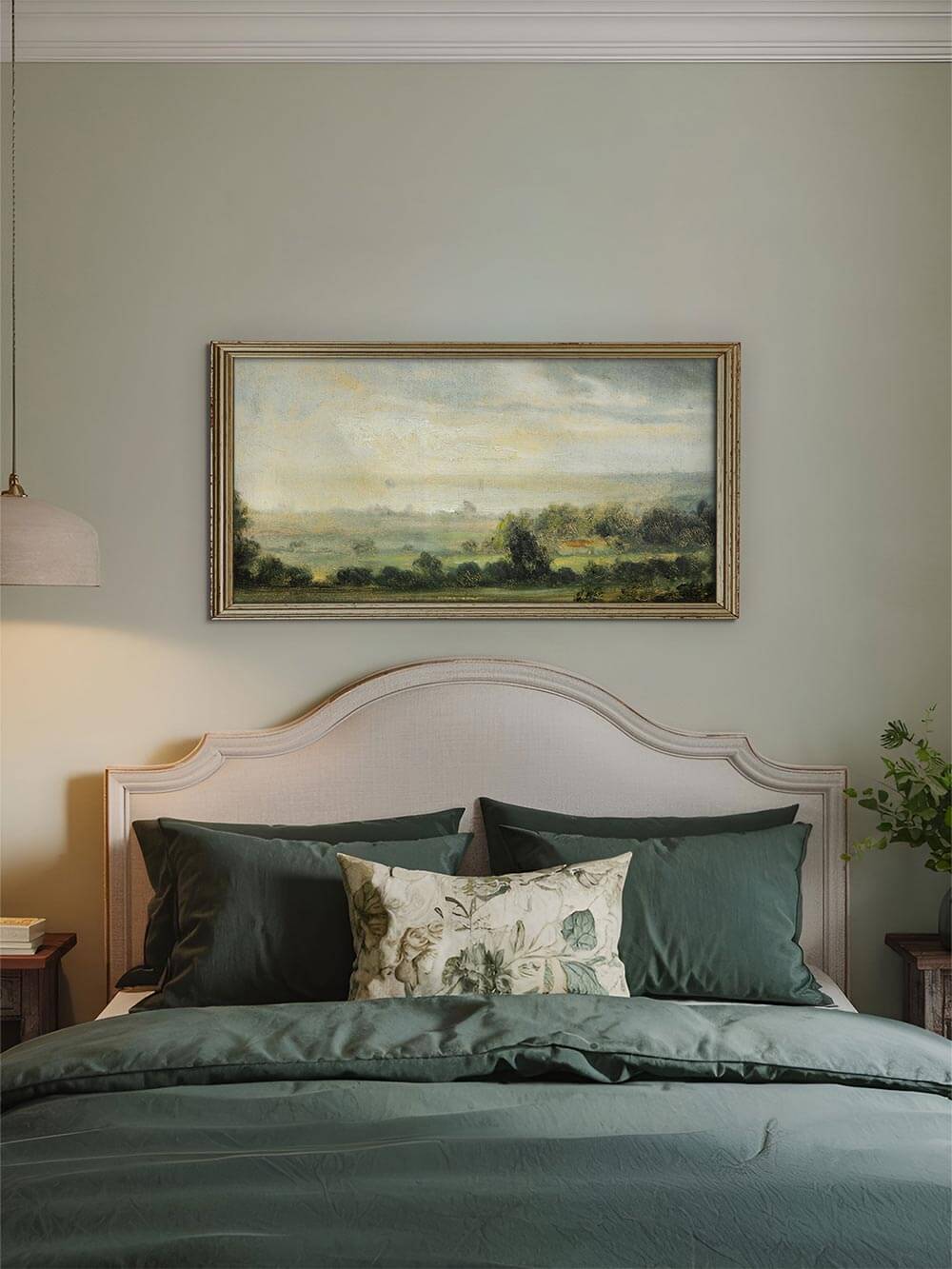 Romantischer Landschaftskunstdruck über einem Bett mit grüner Bettwäsche, eingerahmt in Antikgold, zeigt eine weite Landschaft mit sanftem Licht – ideal für eine beruhigende Atmosphäre im Schlafzimmer.