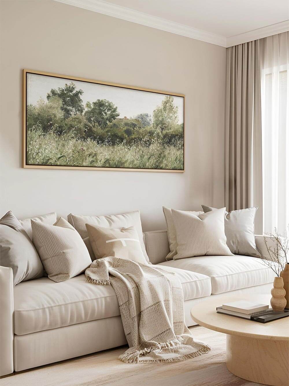 Landschafts-Kunstdruck über einem cremefarbenen Sofa mit hellen Textilien in einem modernen, neutralen Wohnzimmer. Die weichen Grüntöne des Wandbilds bringen Ruhe und Eleganz in minimalistische Interiors.