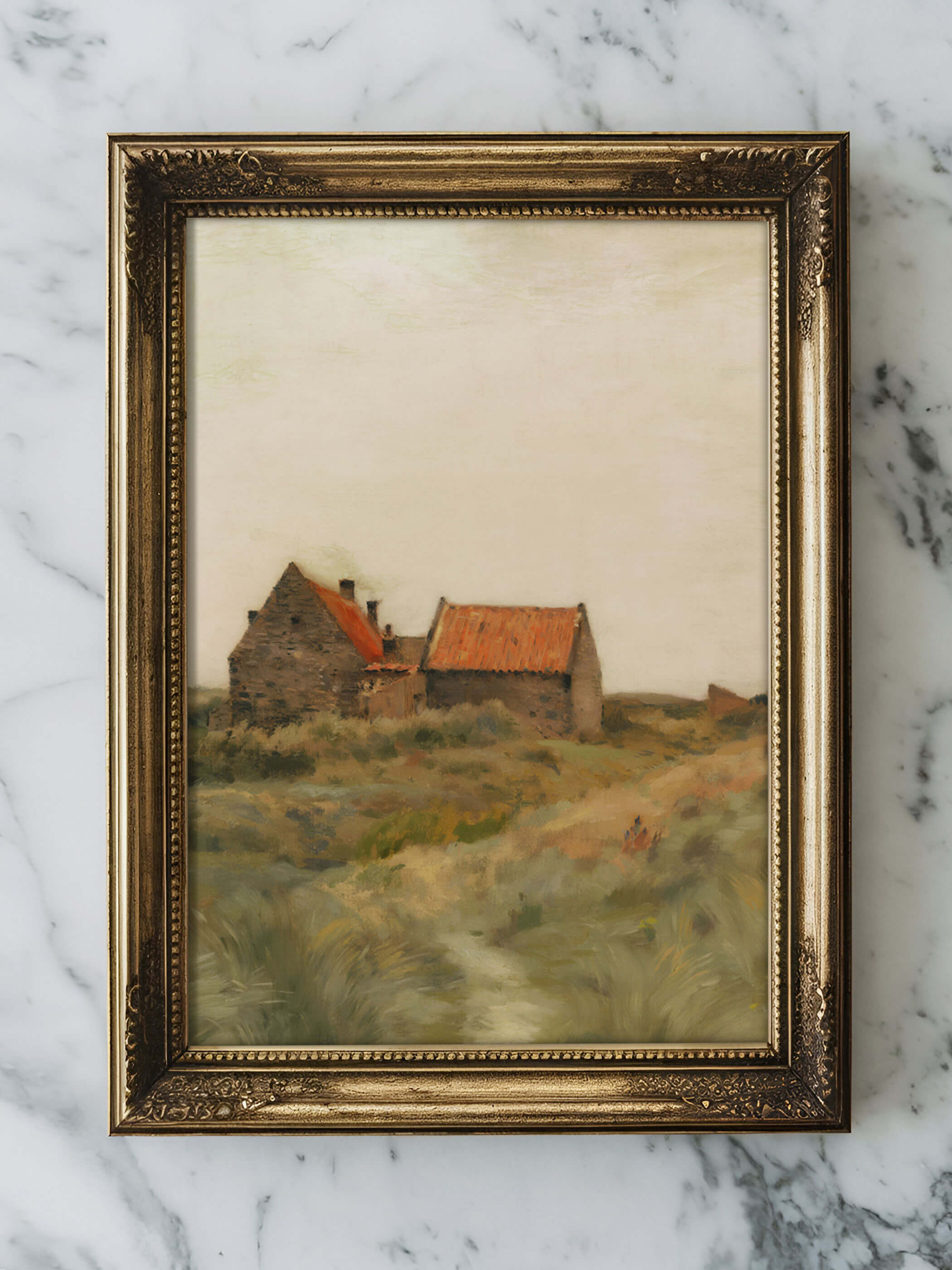 Detailaufnahme des Kunstdrucks eines ländlichen Steinhauses mit roten Ziegeldächern, gerahmt in einem goldenen Rahmen und auf einer Marmoroberfläche ausgestellt.