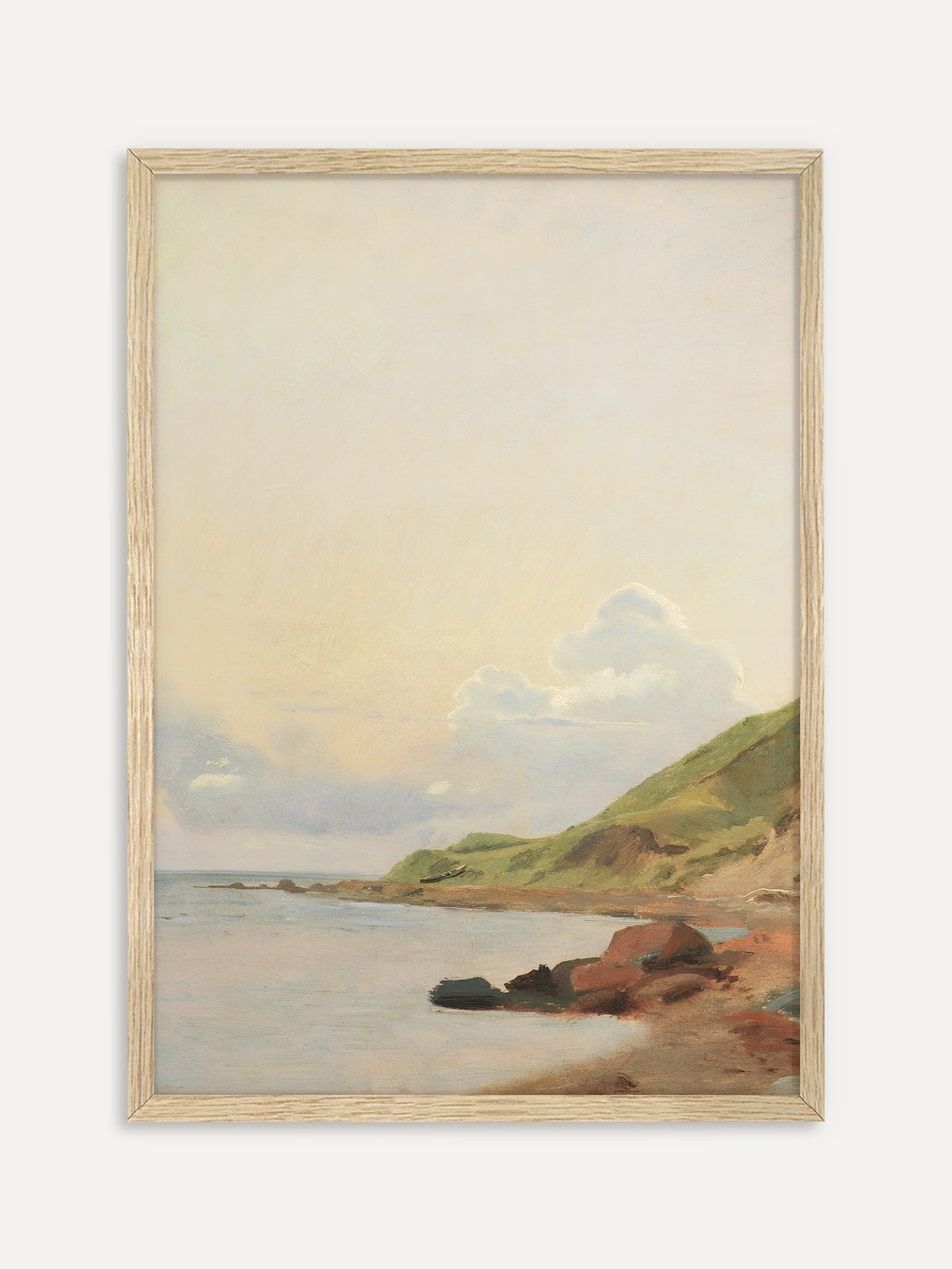 Kunstdruck, der eine stille Bucht mit hellem Wasser, rötlichen Felsen am Strand und einem grünen Hügel unter einem weiten, sanft gelben Himmel mit weißen Wolken zeigt. Im Rahmen aus hellem Holz wirkt die Küstenlandschaft leicht und passt gut in Japandi-Räume. #Rahmen_Helles Holz
