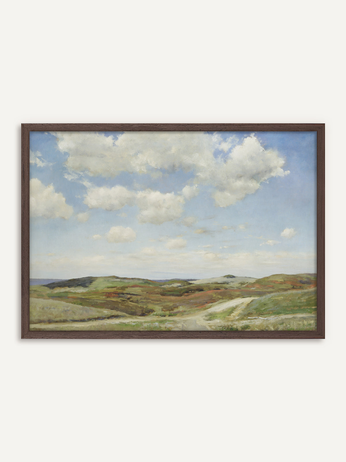 Poster, das eine Dünenlandschaft mit weißen Sommerwolken über sandigen Hügeln zeigt, bewachsen mit Heide in Grün und Rostrot, durch die ein heller Weg zum Meer führt. Der Rahmen aus dunklem Holz greift das Rostrot der Heide auf und gibt dem Motiv Wärme. #Rahmen_Dunkles Holz