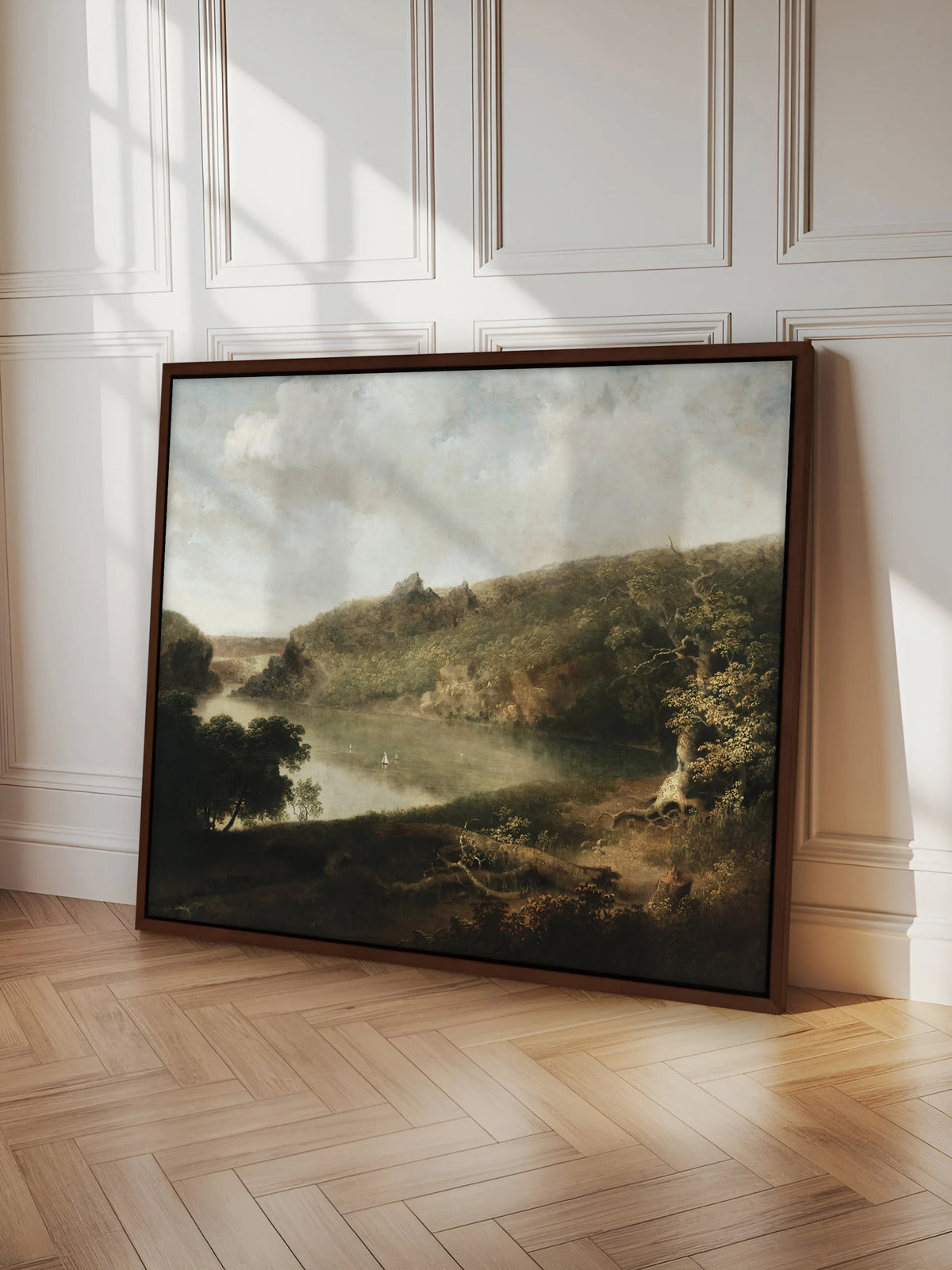 Großes Landschaftsbild mit See im braunen Schattenfugenrahmen, angelehnt an eine weiße Kassettenwand. Es steht auf hellem Fischgrätparkett, Sonnenlicht fällt schräg über Bild und Wand.