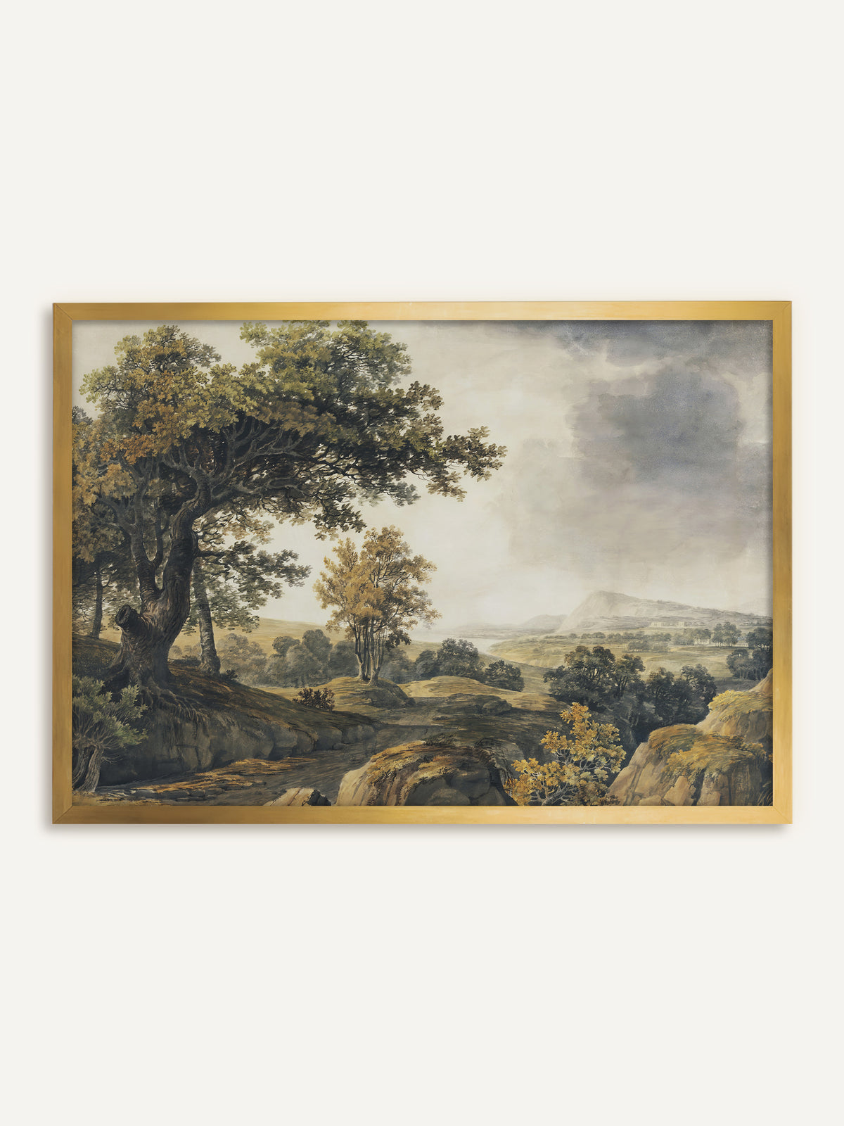 Wandbild, das eine weite Landschaft mit einer alten Eiche am Hang, einem Felsweg und Bäumen in Grün und Ocker unter grauen Regenwolken zeigt, in der Ferne ein Berg über einem See. Im goldenen Rahmen greift das Bild die Ockertöne des Laubs auf und wirkt wie ein antikes Gemälde. #Rahmen_Gold
